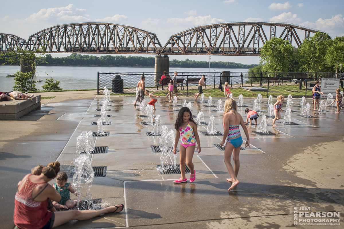 June 23, 2016  Families enjoy the first day of summer playing in the spray park at Henderson, Ky as a northbound CSX E302 (Stilesboro, GA - Evansville, IN (EVWR) makes its way north over the Ohio River Bridge on the Henderson Subdivision. - Tech Info: 1/1250 | f/2.8 | ISO 100 | Lens: Sigma 24-70 @ 32mm with a Nikon D800 shot and processed in RAW.