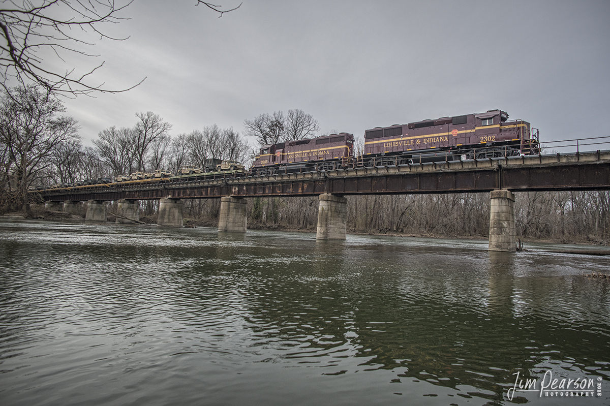 November 23, 2018 - Louisville & Indiana Railroad 2302 and 2003 lead a loaded military train over the Flatrock River at Columbus, Indiana as it makes its way north to deliver its cargo to Camp Atterbury, Indiana.

Camp Atterbury, located in south-central Indiana, about 4 miles west of Edinburgh, Indiana, serves as a military and civilian training base under the auspices of the Indiana National Guard.

The Louisville and Indiana Railroad (reporting mark LIRC) is a Class III railroad that operates freight service between Indianapolis, Indiana and Louisville, Kentucky, with a major yard and maintenance shop in Jeffersonville, Indiana.

According to Wikipedia: The 106-mile line was purchased from Conrail in March 1994. Previous to Conrail, the line was owned by Penn Central, and before that, the Pennsylvania Railroad. It serves the cities of Franklin, Sellersburg, Seymour and Columbus, Indiana, and also serves the former Clark Maritime Center, now Port of Indiana, Jeffersonville. In Louisville, the LIRC interchanges with the Paducah and Louisville Railway, CSX Transportation and the Indiana Rail Road, former Canadian Pacific Railway (via trackage rights over CSX's former Monon line). Traffic from them mostly is potash. In Indianapolis, the line interchanges with CSX Transportation at Avon Yard approximately 7 miles west of the Circle City.