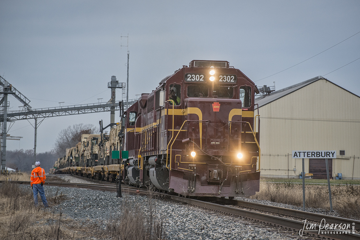 November 23, 2018 - A Louisville & Indiana Railroad worker waits to throw the switch at Atterbury, as 2302 and 2003 lead a loaded military train back south at Atterbury, after the power ran around the train. Here they're pulling back past the switch before backing their train into Camp Atterbury, Indiana.

Camp Atterbury, located in south-central Indiana, about 4 miles west of Edinburgh, Indiana, serves as a military and civilian training base under the auspices of the Indiana National Guard.

The Louisville and Indiana Railroad (reporting mark LIRC) is a Class III railroad that operates freight service between Indianapolis, Indiana and Louisville, Kentucky, with a major yard and maintenance shop in Jeffersonville, Indiana.