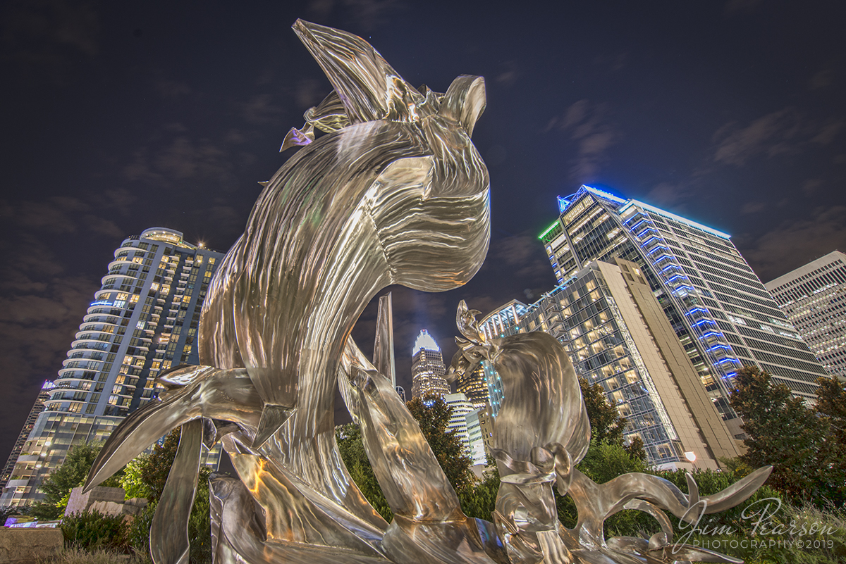 July 25, 2019 - Another long exposure photograph from uptown Charlotte, North Carolina of a steel sculpture called "Spiral Odyssey" against the city skyline.

According to the Qcitymetro website: The Sculpture is a stunning tribute to native son Romare Bearden by Richard Hunt.

The name Spiral Odyssey is a triple tribute. It honors Bearden, the master collage maker who co-founded the New York group Spiral in 1963 to encourage African-American artists. It refers to Homers Odyssey, which Bearden explored multiple times in his work. And it hints at the two-decade friendship between Bearden and Chicago sculptor Richard Hunt.

The piece can be called abstract, but your mind shapes bits of it into figures: the ships body, its billowing sail (or is that a wave?), perhaps a leaping dolphin. Hunt crafted slender arcs of steel so that light falling on them appears to ripple, like a current passing across water.