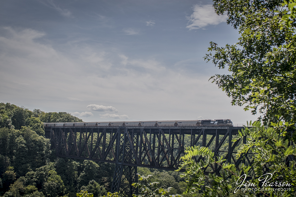 August 10, 2019 - Norfolk Southern engine 1029 leads a grain train north across the NS cantilever bridge over the Kentucky River at High Bridge, Kentucky from the CNO&TP First District. 

According to Wikipedia: High Bridge is a railroad bridge crossing the Kentucky River Palisades, that rises approximately 275 feet from the river below and connects Jessamine and Mercer counties in Kentucky. Formally dedicated in 1879, it is the first cantilever bridge constructed in the United States. It has a three-span continuous under-deck truss used by Norfolk Southern Railway to carry trains between Lexington and Danville. It has been designated as a National Civil Engineering Landmark.

In 1851, the Lexington & Danville Railroad, with Julius Adams as Chief Engineer, retained John A. Roebling to build a railroad suspension bridge across the Kentucky River for a line connecting Lexington and Danville, Kentucky west of the intersection of the Dix and Kentucky Rivers. In 1855, the company ran out of money and the project was resumed by Cincinnati Southern Railroad in 1873 following a proposal by C. Shaler Smith for a cantilever design using stone towers designed by John A. Roebling (who designed the Brooklyn Bridge).

The bridge was erected using the cantilever design with a three-span continuous under-deck truss and opened in 1877 on the Cincinnati Southern Railway. It was 275 feet (84 m) tall and 1,125 feet (343 m) long: the tallest bridge above a navigable waterway in North America and the tallest railroad bridge in the world until the early 20th century. Construction was completed using 3,654,280 pounds of iron at a total cost of $404,373.31. In 1879 President Rutherford B. Hayes and Gen. William Tecumseh Sherman attended the dedication.

After years of heavy railroad use, the bridge was rebuilt by Gustav Lindenthal in 1911. Lindenthal reinforced the foundations and rebuilt the bridge around the original structure. To keep railroad traffic flowing, the track deck was raised by 30 feet during construction and a temporary trestle was constructed. In 1929, an additional set of tracks was built to accommodate increased railroad traffic and the original limestone towers were removed.

The bridge is still accessible by Kentucky State Route 29. In 2005 the state and county jointly reopened a park near the bridge (which had been closed since the mid 1960s) at the top of the palisades above the river. It included a restored open air dance pavilion, first used in the 19th century; as well as a new playground, picnic area, and viewing platform that overlooks the bridge and river's edge from the top of the palisades.