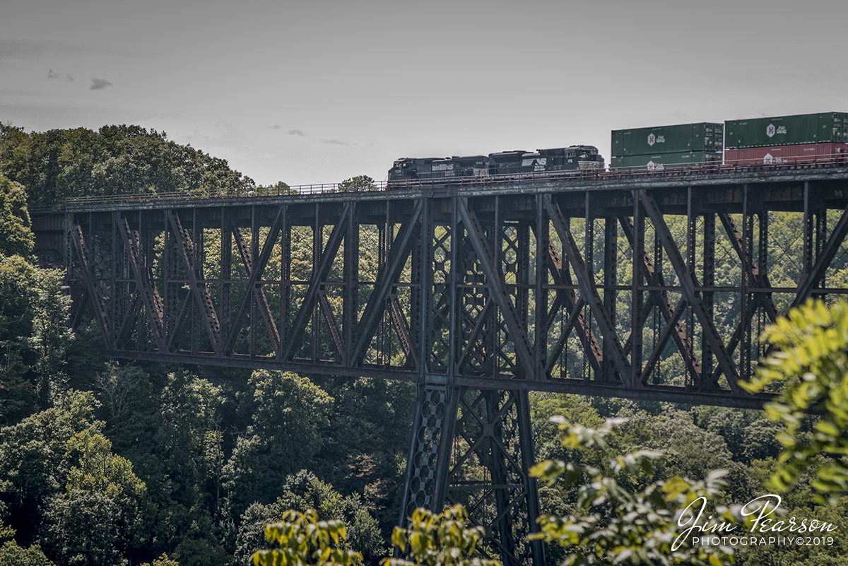 August 10, 2019 - Norfolk Southern engine 9318 leads a intermodal across the NS cantilever bridge over the Kentucky River at High Bridge, Kentucky as it heads south on the CNO&TP First District, also known as the Rathole.

According to Wikipedia: High Bridge is a railroad bridge crossing the Kentucky River Palisades, that rises approximately 275 feet from the river below and connects Jessamine and Mercer counties in Kentucky. Formally dedicated in 1879, it is the first cantilever bridge constructed in the United States. It has a three-span continuous under-deck truss used by Norfolk Southern Railway to carry trains between Lexington and Danville. It has been designated as a National Civil Engineering Landmark.

In 1851, the Lexington & Danville Railroad, with Julius Adams as Chief Engineer, retained John A. Roebling to build a railroad suspension bridge across the Kentucky River for a line connecting Lexington and Danville, Kentucky west of the intersection of the Dix and Kentucky Rivers. In 1855, the company ran out of money and the project was resumed by Cincinnati Southern Railroad in 1873 following a proposal by C. Shaler Smith for a cantilever design using stone towers designed by John A. Roebling (who designed the Brooklyn Bridge).

The bridge was erected using the cantilever design with a three-span continuous under-deck truss and opened in 1877 on the Cincinnati Southern Railway. It was 275 feet (84 m) tall and 1,125 feet (343 m) long: the tallest bridge above a navigable waterway in North America and the tallest railroad bridge in the world until the early 20th century. Construction was completed using 3,654,280 pounds of iron at a total cost of $404,373.31. In 1879 President Rutherford B. Hayes and Gen. William Tecumseh Sherman attended the dedication.

After years of heavy railroad use, the bridge was rebuilt by Gustav Lindenthal in 1911. Lindenthal reinforced the foundations and rebuilt the bridge around the original structure. To keep railroad traffic flowing, the track deck was raised by 30 feet during construction and a temporary trestle was constructed. In 1929, an additional set of tracks was built to accommodate increased railroad traffic and the original limestone towers were removed.

The bridge is still accessible by Kentucky State Route 29. In 2005 the state and county jointly reopened a park near the bridge (which had been closed since the mid 1960s) at the top of the palisades above the river. It included a restored open air dance pavilion, first used in the 19th century; as well as a new playground, picnic area, and viewing platform that overlooks the bridge and river's edge from the top of the palisades.