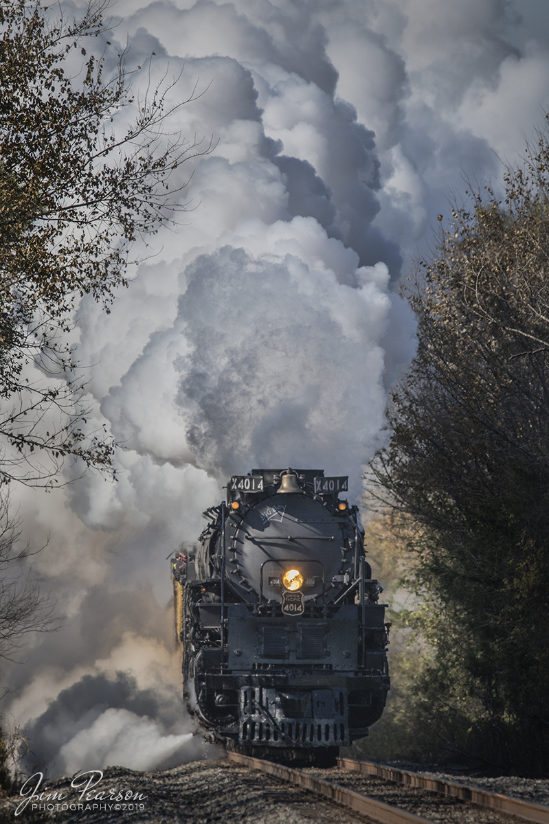November 13, 2019 - Union Pacific's Race Across the Southwest was on the move again as UP 4014 Big Boy heads through the countryside just north of Prescott, Arkansas on its way north on UP's Little Rock Subdivision on a beautiful and cold fall morning. As you can tell the cold weather went a long way in producing beautiful plumes of steam!!

Did You Know: As if the 4000s werent big enough, the Union Pacific actually contemplated ordering five additional 4-8-8-4s that would be even larger. As World War II dragged on, the U.P. needed additional power on its line to Los Angeles through southwest Utah. 

According to an article by historian and artist Gil Bennett (Classic Trains, Spring 2019), plans were on the drawing board to build #4025-4029. This third class of Big Boys was to measure 139 feet, 11 5/8 inches long and weighs just under 1.3 million pounds. All would be oil fired, instead of coal. The locomotive, itself, would be a foot longer than existing Big Boys. The tender was to be extended to just over 54 feet long in order to accommodate a 33,000 gal. water tank. 

By comparison, #4014 and it's tender is 132 feet, 9 7/8 inches long. Its water tank holds 24,000 gals. When the war ended in September 1945, at least a year, if not two, ahead of some predictions, the need for extra steam powered locomotives became a moot point. 

The bigger Big Boy idea was dropped and the Union Pacific, like most other major railroads, concentrated on shifting to diesel power.