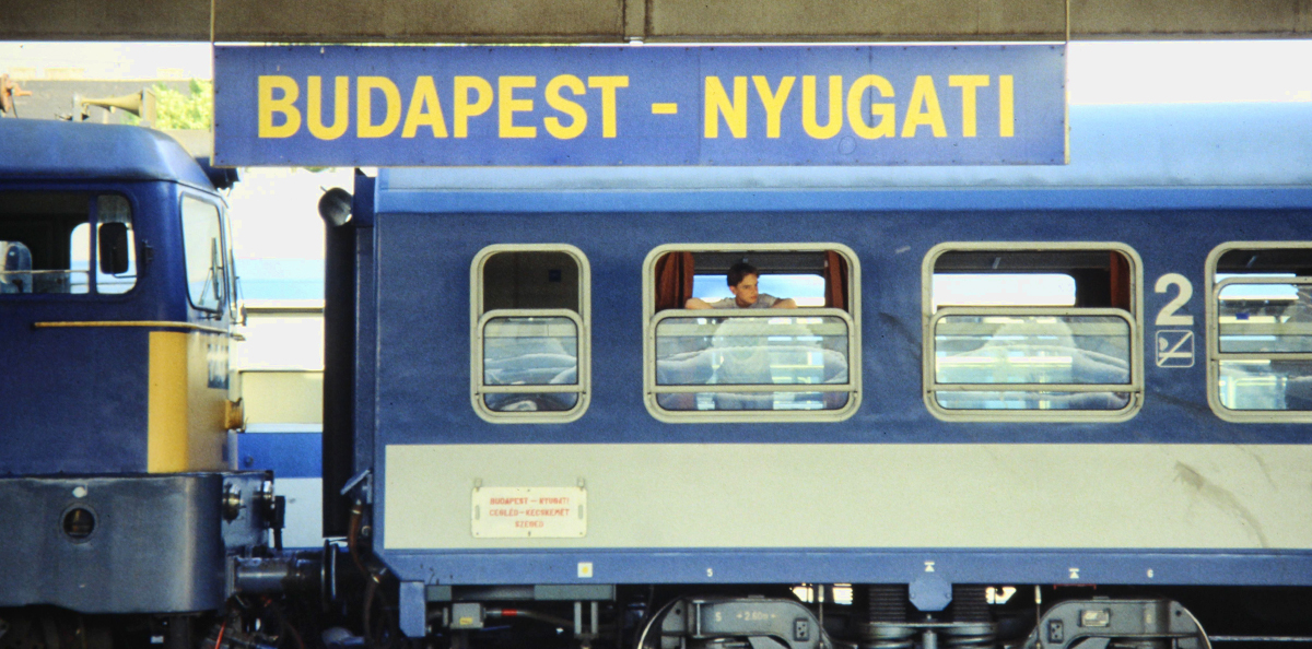 Blast From The Past - Summer 1994 - A teenager waits patiently for his train to depart the Budapest-Nyugati train station in Budapest, Hungary. 

According to Wikipedia: The Nyugati pályaudvar (English: Western railway station), generally referred to simply as Nyugati, is one of the three main railway terminals in Budapest, Hungary. The station is on the Pest side of Budapest, accessible by the 4 and 6 tramline and the M3 metro line.

The station was planned by August de Serres and was built by the Eiffel Company. It was opened on 28 October 1877. Previously another station stood in its place, the end station of Hungary's first railway line, the PestVác line (constructed in 1846). This building was pulled down in order to construct the Grand Boulevard (Nagykörút) which is now smaller than the outer ringroad (Hungária körút - Hungary Boulevard) and the recently opened motorway ringroad M0 (2008).