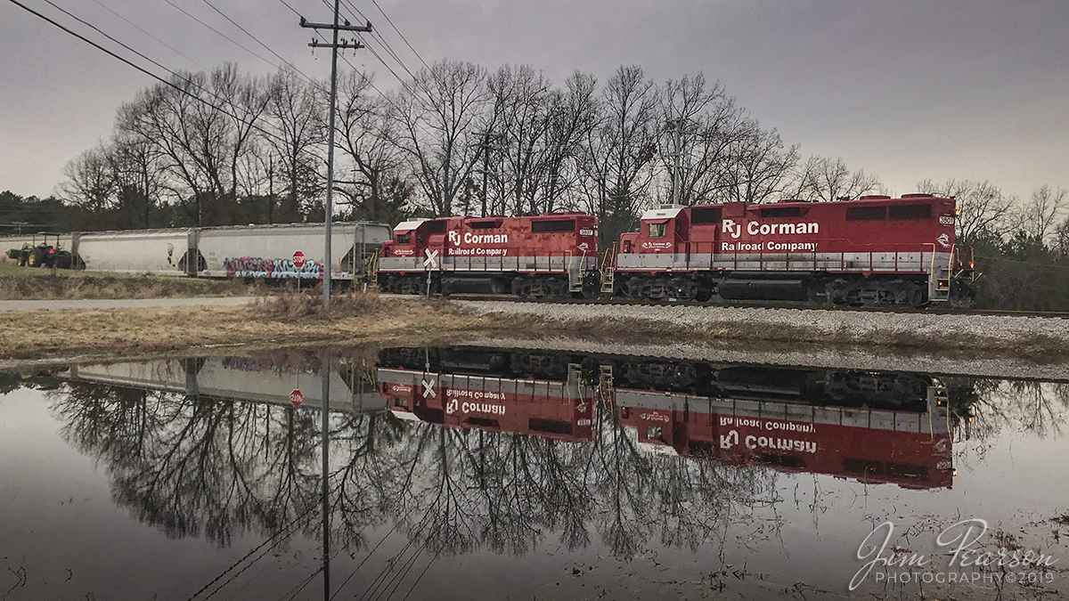 December 20, 2019 - The RJ Corman Cumberland City Turn is reflected in a small pond as it crosses over Dunlop Road as it continues its move north on the Memphis Line after making a pickup at Letica Plastics in Clarksville, Tennessee.