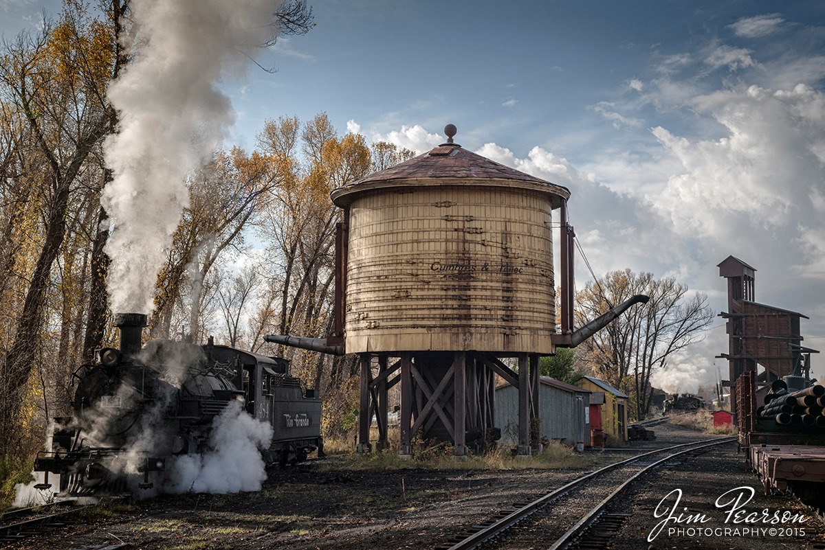 Blast From The Past - October 20, 2015 - Cumbres & Toltec Scenic Railroad Locomotive 484 sits next to the water tower at Chama, New Mexico, after the last day of scheduled revenue runs for the year. Chama is one of my favorite steam operations to photograph!

According to Wikipedia: The Cumbres & Toltec Scenic Railroad, often abbreviated as C&TSRR, is a 3 ft (914 mm) narrow-gauge heritage railroad running for 64 miles (103 km) between Antonito, Colorado and Chama, New Mexico, United States. The railroad gets its name from two geographical features along the route, the 10,015-foot (3,053 m)-high Cumbres Pass and the Toltec Gorge. Originally part of the Denver and Rio Grande Western Railroad's narrow-gauge network, the line has been jointly owned by the states of Colorado and New Mexico since 1970.

The rail line over which the Cumbres & Toltec operates was constructed in 1881 by the Denver and Rio Grande Western Railroad (D&RGW) as part of their San Juan extension stretching from Alamosa, Colorado to Durango, Colorado. The line was originally built to support mining operations in the San Juan Mountains, mainly around Durango and Silverton. By the mid 20th century, the ore traffic had dwindled but the line continued to support various agricultural and industrial operations until the 1960s.

In 1968, freight traffic was virtually gone and the railroad began the process of abandoning the line. However, the states of Colorado and New Mexico purchased the 64 mile portion between Antonito and Chama in 1970 and began excursion services on the route as the Cumbres & Toltec Scenic Railroad.

The Cumbres & Toltec Scenic Railroad operates between late May and late October with two trains (one in each direction) departing each morning from Antonito and Chama. Both trains are timed to meet at Osier, an old section town located about halfway along the route, for a lunch stop. Afterwards, passengers continue with their train to its destination or switch trains to return to their original terminal. Through riders are returned to their starting place by motorcoach after the train arrives at its destination.

In addition to the through service, the C&TSRR operates various special excursions during the season such as dinner trains. On certain days during the holiday season, the railroad offers special "Santa Trains" from both Chama and Antonito and guests are encouraged to bring gifts and/or food for the less fortunate.