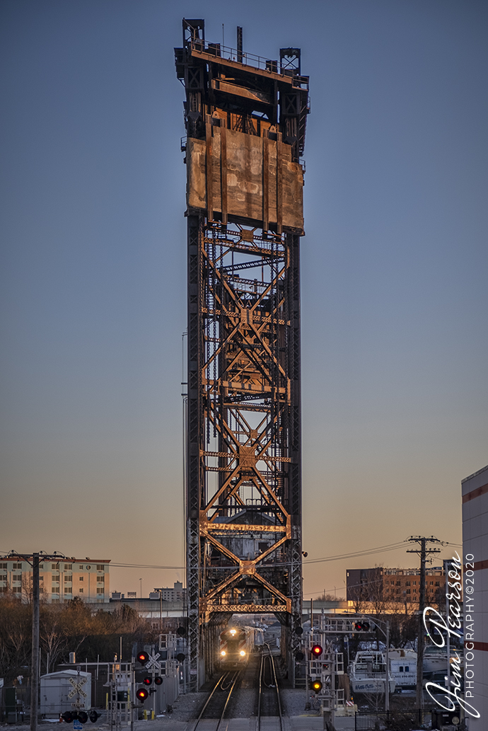 February 20, 2020 - A northbound Metra train crosses the 21st Street Lift Bridge over the old Pennsylvania RR Drawbridge 463, as it heads north to Union Station in downtown Chicago at dusk. This lift bridge is one of only a few still in operation in Chicago, Illinois.

According to Patrick McBriarty, a former business person and consultant who over a decade ago discovered a new focus and fascination for Chicago bridges. The bridge was Designed by engineers J.A.L. Wadell and John Harrington. It is the second vertical-lift bridge ever built crossing the Chicago River, and only one still standing.  It's near Chinatown over the South Branch of the river and was completed in 1915 for the Pennsylvania Railroad. The bridge is now owned by Amtrak and carries Metra and Norfolk Southern train traffic in and out of Chicago.