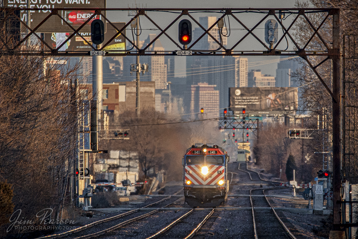 February 21, 2020 - Metra engine 141 heads up an evening commuter  train as it heads out of Chicago, Illinois toward Norwood Park Station as the late evening light rakes across the downtown skyline.