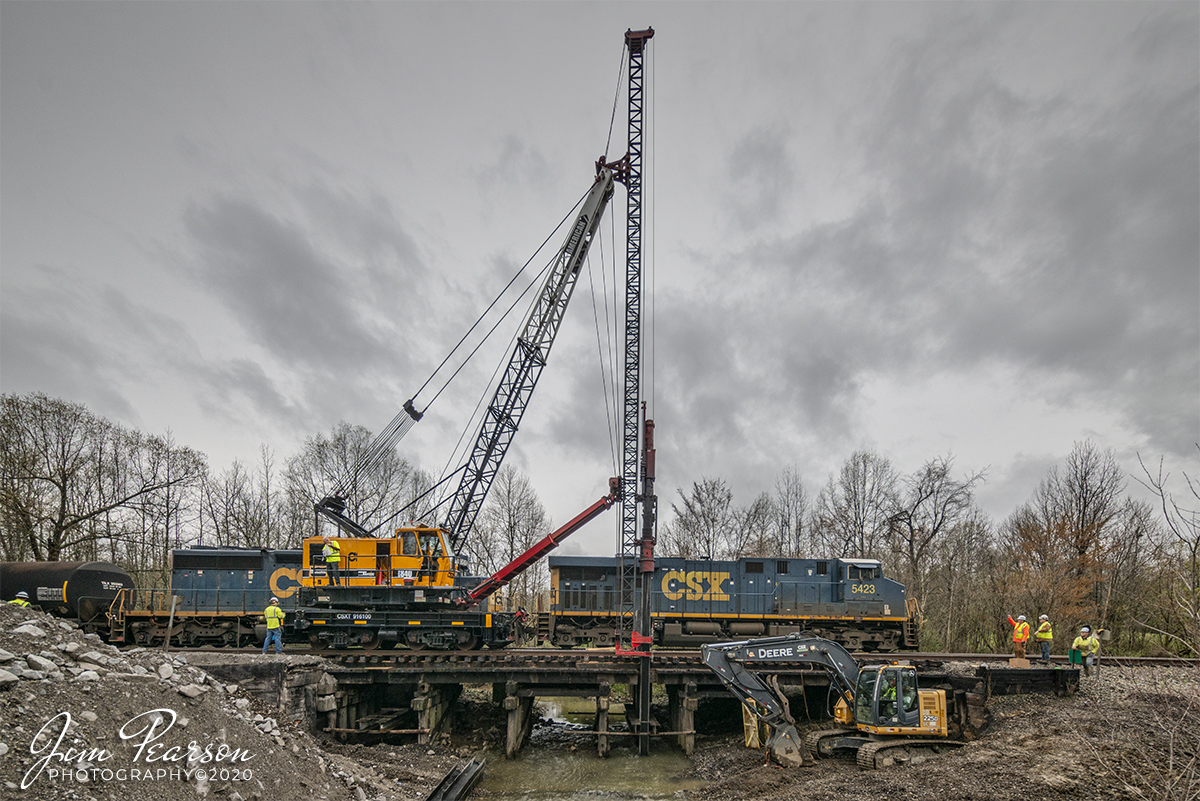 March 31, 2020 - A CSX bridge work crew keeps a watchful eye and sends a friendly wave to the crew of CSX as Q502 crosses over the Craborchard Creek bridge, as CSXT mobile crane 916100 sits idle, as the manifest heads north through their work zone on the Henderson Subdivision at Nortonville, Ky. The crane is an AMERICAN Model 840 Locomotive Crane with a pile driver attached.

The bridge crew is working on installing new pilings for the bridge over Craborchard Creek using the pile driver attached to the crane. I'll be posting a video on the operation later today if you're interested in seeing and hearing it work.

Here's more information on the crane if you're interested: http://aolcrane.com/pdfs/840850debrochure.pdf