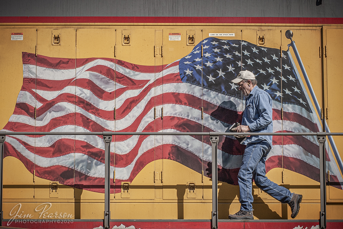 May 1, 2005 - Blast From The Past - The conductor on a Union Pacific freight walks past the American Flag on his engine in the yard at Salem, Illinois.

According to the Union Pacific Website: When we added the flag to our locomotives more than a decade ago  at the suggestion of an employee after 9/11  we followed the tradition of having the Union (the blue field of stars) lead the way, such that on the right-hand side of the vehicle ("passenger side"), the flag would appear reversed. 

Further, the flag was painted to convey the motion of forward movement as if it were billowing with the speed of the locomotive. Having the Union forward on both sides is the overwhelming choice anytime the flag is portrayed on a transport vehicle, from NASA space shuttles to Air Force One.