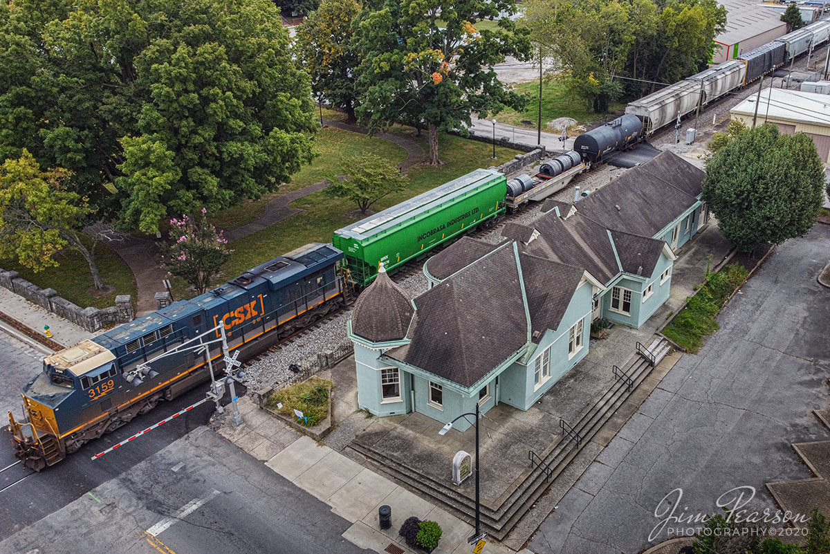 September 26, 2020 - CSXT 3159 leads northbound CSX Q648 past the old Louisville and Nashville (L&N) depot in downtown Hopkinsville, Ky as it heads north on the Henderson Subdivision.

According to Wikipedia: The L & N Railroad Depot in the Hopkinsville Commercial Historic District of Hopkinsville, Kentucky is a historic railroad station on the National Register of Historic Places. It was built by the Louisville & Nashville Railroad in 1892.

The year 1832 saw the first of many attempts to woo a railroad to Hopkinsville. This first attempt was to connect Hopkinsville to Eddyville, Kentucky. In 1868 Hopkinsville finally obtained a railroad station, operated by the Evansville, Henderson, & Nashville Railroad. The Louisville & Nashville Railroad acquired the railroad in 1879.

The Hopkinsville depot is a single-story frame building with a slate roof. It has six rooms: a Ladies Waiting room (the room closest to the street), a General Waiting Room, a Colored Waiting Room, a baggage room (the furthest room from the street), a ticket office (the only room which connected to all three waiting rooms), and a ladies' restroom. Immediately outside were warehouses for freight, usually tobacco.

Its last long distance train was the Louisville and Nashville's Georgian, last operating in 1968.

During its operating years, the Hopkinsville depot was a popular layover spot for those traveling by train. It was the only Louisville & Nashville station between Evansville, Indiana and Nashville, Tennessee where it was legal to drink alcohol. Hopkinsville got the nickname "Hop town" due to train passengers asking the conductors when they would arrive at Hopkinsville, so they could "hop off and get a drink".

The Hopkinsville L & N Railroad Depot was placed on the National Register of Historic Places on August 1, 1975. It was last used by the Pennyrile Arts Council and from what I last heard it is empty. CSX, which bought out the Louisville & Nashville, still run trains on the tracks next to the depot, but do not stop.

Tech Info: DJI Mavic Mini Drone, JPG, 4.5mm (24mm equivalent lens) f/2.8, 320, ISO 100.