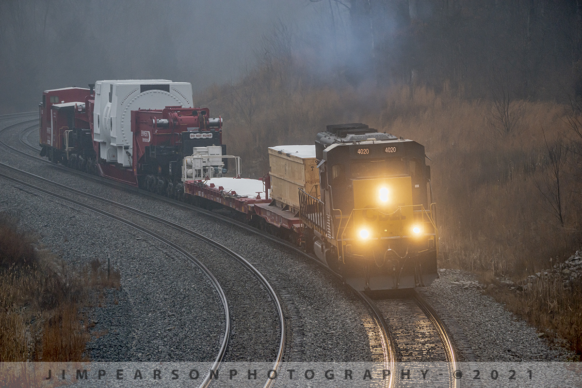 Southbound CSX W992-06 High and Wide

I was on my way North on Main Street here in Madisonville, Ky, through the heavy overcast and misty freezing rain yesterday, February 10th, 2021, when I encountered CSX high and wide train W992-06 heading south on the Henderson Subdivision.

I hadn't received any heads up on this move from my friends to the north and so I was caught completely by surprise when I saw the red caboose on the end of this shot train! I immediately made a u-turn and the chase was on!

While the predicted ice storm was passing through our area, the temperatures were slightly above freezing and I knew the roads were just wet and not ice coated yet, plus I knew that this train would be moving at a restricted speed of 25mph, which is normal for high and wide moves and that I wouldn't have any problems keeping ahead of it as I got to some good spots to catch it's move, despite the bad weather.

This was my first spot which is the S curve approaching the New Salem Church overpass in Nortonville, Kentucky.

It was a Emmert International train move with CSXT SD40-3 #4020 as power and BBCX 1002 as the trailing caboose with what appeared to be a steam generator of some sort. It was being hauled on their BBCX1000 Schnabel Railcar.

According to the Emmert International website: "Emmert International's BBCX1000 Schnabel Railcar is specifically designed to carry heavy (up to 1 million pounds) and oversized loads in such a way that the load itself makes up part of the car. The load is suspended between the two ends of the cars by lifting arms; the lifting arms are connected to a pivot above an assembly of pivots and frames that carry the weight of the load and the lifting arm.

For loads not designed to be part of the car Emmert International's BBCX1000 is equipped with a deck designed to carry the loads in standard configuration up to 836,000 pounds. Customized decks can be manufactured to increase the overall payload weight. Emmert International's BBCX1000 is equipped with hydraulic equipment that will either lift the load vertically or horizontally shift the load while in transit to clear obstructions along the car's route.

With 20 axles (ten for each half) containing four trucks connected by a complex system of span bolsters its tare (unloaded) weight without deck is 424,000 lbs. The BBCX1000's empty car length is 115'10" with a maximum length with the loading deck at 168 9". Maximum vertical load shifting ability is 14 and the maximum horizontal load shifting ability is 22". The heavy duty AAR railcar mechanical designation is LS."

Emmert International's BBCX1000 Schnabel Railcar is accompanied by the BBCX 1002 Caboose and BBCX1003 flat car that carries the deck when not in service. The BBCX1000 is pulled by special train service and requires 2 operators. When in transport not carrying loads the BBCX is limited to 40 mph. When loaded or empty with deck in place the BBCX1000 is limited to 25 mph.

Tech Info: Nikon D800, RAW, Sigma 150-600 @290mm f/7.6, 1/640, ISO 640.