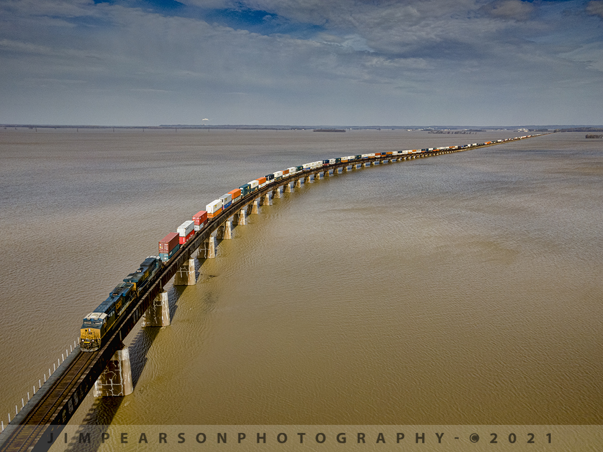 CSX Q025 Southbound over the Ohio River Floodwaters

This is a shot that I've been wanting to get even before I started flying a drone! A shot of a train passing over the floodwaters from the Ohio River as it heads across the river at Henderson, Kentucky coming out of Evansville, Indiana. This  is a shot that one could only get with a john boat in the past and I neither had one or knew anyone with one, so this has always been a dream shot for me!

With the partly cloudy skies I was worried that I wouldn't have sunlight for the shot, but as you can see with the broken clouds on March 10th, 2021, they parted enough for this dramatic lighting as CSX hot intermodal Q025-10  made its way up the viaduct to the bridge over the Ohio River heading south into Henderson, Ky on the CSX Henderson Subdivision.

The scene as far as the eye can see here is normally farmers fields, but today it was an extension of the Ohio River as it was right at 37 feet above flood stage as the train passed over it.

Tech Info: DJI Mavic Air 2 Drone, RAW, 4.5mm (24mm equivalent lens) f/2.8, 1/640, ISO 100.