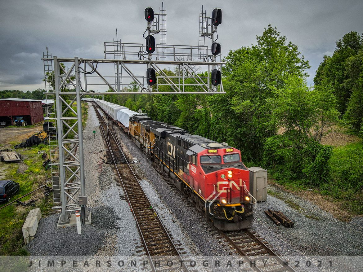 CN 2852 leads Northbound W986 at Robards, Ky with Windmill Train

We get trains on the CSX Henderson Subdivision from time to time that haul windmill motors and housings, but this is the first I can recall being led by a Canadian National and Union Pacific locomotive!
It was early morning on May 4th, 2021 when I first heard that this train was finally making its way up the Henderson Subdivision from Nashville, Tennessee. I found this out after I had already committed to going to Evansville, Indiana to chase CSX W992-28, the high and wide move that was tied down at Harwood Siding in Evansville. 
Well, after getting there and sitting waiting for a crew (it had been there more than 12hrs) I decided if I wanted a chance to catch a shot and video of W986 that I needed to head back south.
Of course, I did catch the high and wide move the next day and if you havent already you can see a shot of it on any of my sites and a video will be coming soon, but back to W986.
I had planned to catch this train at Rahm where it comes across the Ohio river into Evansville, but with the weather and darkening skies I decided not to chance missing it where I could get a shot with my drone, so I made my way to the north end of Anaconda at Robards, Ky on the Henderson Subdivision and caught it heading south there with CN 2852 leading. 
As you can tell from the photo the light was fading fast and the train was moving fast! I didnt have time to do much more than get the drone up and in position before the train hit this spot. If I had gotten there a bit earlier, I probably would have boosted my ISO a little, to up the shutter speed, but actually I think I like the little bit of motion blur on the lead unit as it gives a feeling of speed! Details below on the Tech stuff!

Tech Info: DJI Mavic Air 2 Drone, RAW, 4.5mm (24mm equivalent lens) f/2.8, 1/80, ISO 100.