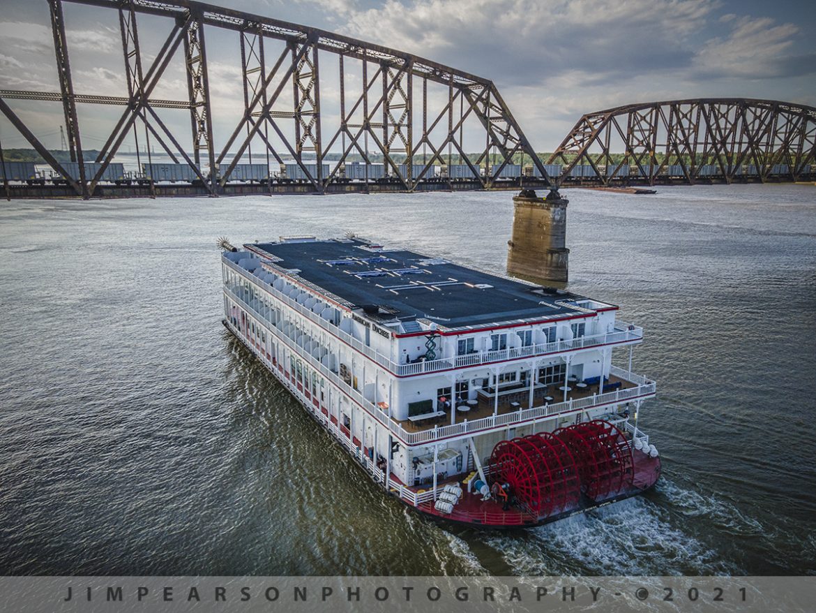 The American Duchess passing under CN U72481-05 at West Paducah, KY

The American Duchess, a river cruise paddle-wheeler owned and operated by American Queen Steamboat Company passes under southbound Canadian National U72481-05 on the bridge over the Ohio River between Metropolis, IL and West Paducah, KY. U72481-05 is carrying a load of Iron ore from Keenan, MN to Convent, LA on the CN Bluford Subdivision.

According to Wikipedia: The American Duchess is a river cruise paddle-wheeler owned and operated by American Queen Steamboat Company (AQSC). It is the third addition to their fleet and is advertised as being the most luxurious option of the line's vessels. The riverboat's itineraries include routes on the Mississippi, Ohio, Tennessee, Cumberland, and Illinois Rivers.

Before it was American Duchess, this vessel was originally designed and built for Isle of Capri Casinos as a casino boat named Bettendorf Capri.

After going land-based, Isle of Capri sold the paddle-wheeler to AQSC in 2016. On October 16, 2016, Bettendorf locals gathered on the levee to give their farewell to the 21-year-old casino boat and watched her pull off the riverbank to sail south to undergo her reconstruction. 

Contracted to Bollinger Shipyards in Morgan City, Louisiana, the vessel would be gutted, remodeled, and relaunched as a river cruise liner the following year. The conversion from a casino boat to an overnight passenger vessel involved the removal of over 1,000 slot machine bases and 1,200 steel chairs, the construction of new dividing walls to form 83 passenger cabins, the addition of a crew hold, a completely new interior layout and design, modifications to propulsion and a new exterior paint job.

Tech Info: DJI Mavic Air 2 Drone, RAW, 4.5mm (24mm equivalent lens) f/2.8, 1/240, ISO 100.