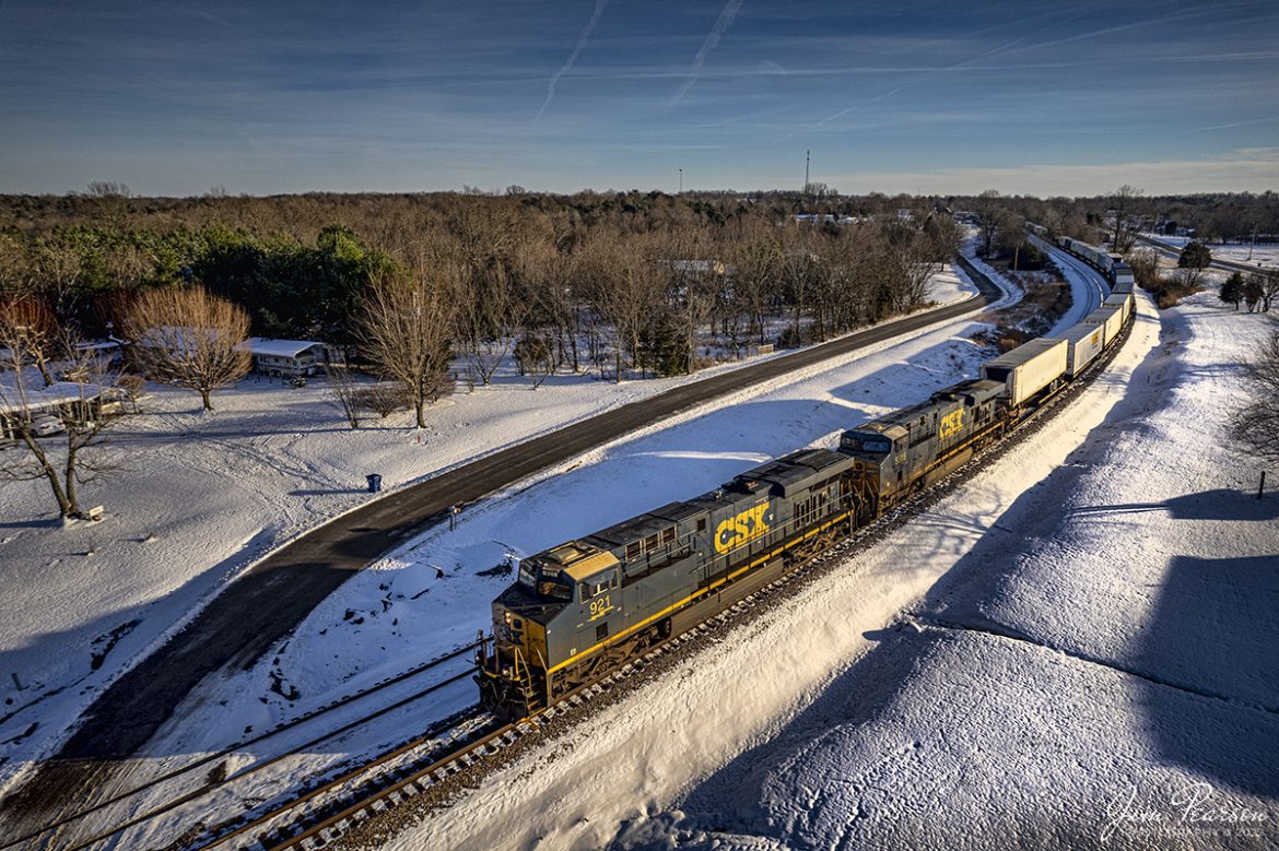 CSXT 921 leads intermodal, I026 (Jacksonville, FL - Bedford Park, IL), as it approaches the north end of Kelly Siding on its way north on the Henderson Subdivision at Kelly, Kentucky, on January 27th, 2022, a late winter afternoon.

From Wikipedia: Kelly is an unincorporated community in Christian County, Kentucky, in the United States. Kelly is located at on U.S. Route 41 and is best known for being the location of the 1955 Kelly-Hopkinsville, KY alien encounter, in which residents reported seeing unidentifiable creatures and lights at a rural farmhouse. In honor of this event, the community hosts the Kelly "Little Green Men" Days festival each year, where visitors can buy "intergalactic souvenirs".

Tech Info: DJI Mavic Air 2 Drone, RAW, 4.5mm (24mm equivalent lens) f/2.8, 1/2000, ISO 120.

#trainphotography #railroadphotography #trains #railways #jimpearsonphotography #trainphotographer #railroadphotographer