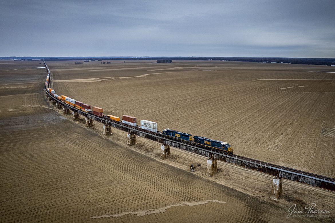 With CSX SD50-3 8619 as the trailing and 3232 leading, hot intermodal I025 (Bedford Park, IL - Moncrief Yard - Jacksonville, FL) climbs the viaduct over the Ohio River flood plain area at Rahm, Indiana, just south of Evansville, IN on January 27th, 2022. 

Here they are approaching the bridge over the Ohio river between Rahm, IN and Henderson, Ky as it makes its way south on the CSX Henderson Subdivision on a cold winter morning!

From the Web: The current viaduct and bridge were built by the L&N railroad and were dedicated on the last day of 1932 at a cost about $4 million. It replaced one erected in 1885, also built by the L&N, which at that time was the longest channel span of that type in the world at 2.3 miles long.

Tech Info: DJI Mavic Air 2 Drone, RAW, 4.5mm (24mm equivalent lens) f/2.8, 1/250, ISO 200.

#trainphotography #railroadphotography #trains #railways #jimpearsonphotography #trainphotographer #railroadphotographer