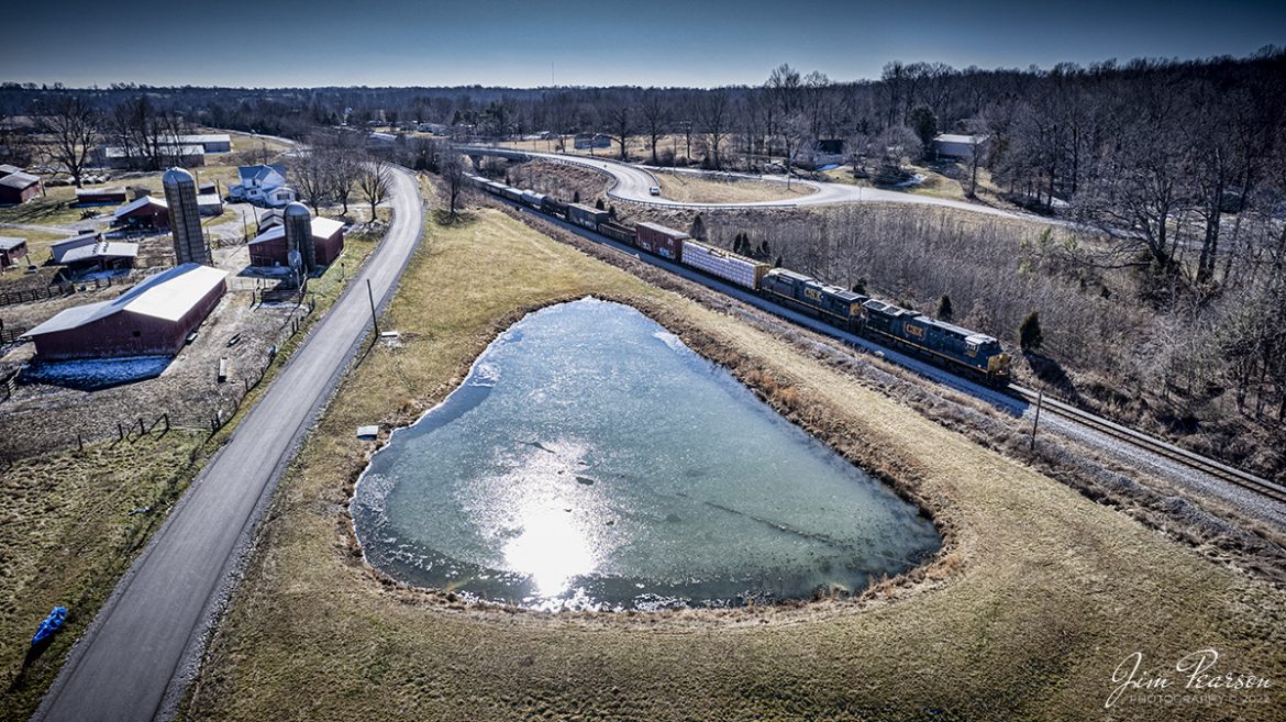 CSXT 3353 and 5360 leads as they pass the pond at the location known as poorhouse on the railroad, as it heads north on the Henderson Subdivision at Madisonville, Ky on February 7th, 2022.

This location at MP 279 on the railroad got its name from the Louisville and Nashville Railway days when the Hopkins County Poorhouse stood near this location.

According to the Kentucky Historic Institutions website: In 1910 there were more than 84 thousand paupers that were enumerated in poorhouses in the United States; this was a marked increase of 3 percent compared to 1904. In Kentucky, the number of enumerated people in poorhouses in 1910 were 1,522; 871 being male and 651 being female. Of that population, 1,044 were native born, 167 were foreign born, 27 have unknown nativity, and 284 were colored. Irish and Swiss immigrants had a much high ratio of pauperism in 1910 than any other nationality.

According to the occupations of individuals admitted into poorhouses, unskilled laborers made up the highest number. Skilled trades also held a relatively considerable number as well. Women frequently were domestic servants prior to admission. A relatively large number of about two filths reported being unable to do any work of any kind. A statistically significant number of paupers during the year 1910 were consider physically or mentally defective though the number of insane and feeble-minded almshouses was on the decline in 1910. Three fourths of discharges were done so as self-supporting. Approximately 17,000 paupers died in poorhouses during 1910 a rate of 207.7 paupers per 1,000. The most common cause of death at that time was tuberculosis of the lungs.

In earlier days, poorhouses were sometimes used as temporary shelters for vagrants as well as a place of detention for petty criminals. This was often due to poorhouses being the only public agency available to offer relief, even to those who were insane, feeble-minded, or epileptic. Some communities combined poorhouses with free hospitals or infirmaries that catered to the poor.

Tech Info: DJI Mavic Air 2 Drone, RAW, 4.5mm (24mm equivalent lens) f/2.8, 1/1600, ISO 100.

#trainphotography #railroadphotography #trains #railways #jimpearsonphotography #trainphotographer #railroadphotographer
