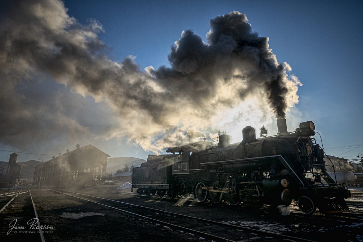 The frigid early morning air and backlight sunlight makes for a dramatic photo with streams of sunlight passing through the steam, as Nevada Northern Railway engine 81 sits outside of the engine house with the railroads Repair in Place building in the background, as the crew gets it ready for another day at Ely, Nevada on February 13th, 2022. 

The Repair in place building, which is better known as the RIP, and during the ore carrying days ore cars led a very rough life, between being banged with shovels, boulders being dropped into them and wear and tear of everyday use. The RIP was built to allow repair of the cars indoors, whereas before they were repaired outdoors all year long. Today the building is used for ongoing restoration projects by the museum.

Nevada Northern No. 81 is a "Consolidation" type (2-8-0) steam locomotive that was built for the Nevada Northern in 1917 by the Baldwin Locomotive Works in Philadelphia, PA, at a cost of $23,700. It was built for Mixed service to haul both freight and passenger trains on the Nevada Northern railway.

According to Wikipedia: The Nevada Northern Railway Museum is a railroad museum and heritage railroad located in Ely, Nevada and operated by a historic foundation dedicated to the preservation of the Nevada Northern Railway.

Tech Info: Nikon D800, RAW, Nikon 10-24mm @ 14mm, f/4, 1/8000, ISO 500.

#trainphotography #railroadphotography #trains #railways #jimpearsonphotography #trainphotographer #railroadphotographer #steamtrains #nevadanorthernrailway