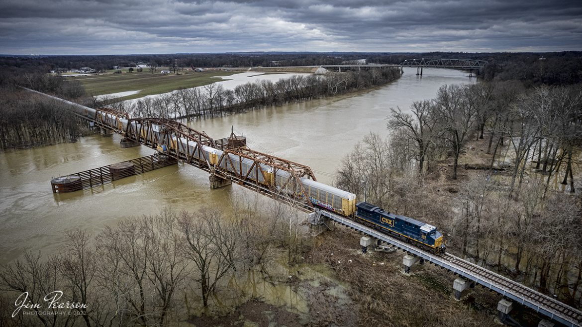 CSX 483 leads CSX Q228 westbound across the CSX Swing Bridge over the Green River at Spottsville, Kentucky on the CSX Texas Line (LH&StL Subdivision) as it makes its way to the Toyota Plant at Princeton, Indiana from Louisville, KY on March 7th, 2022.

This bridge was shut down for well over a year due to mechanical problems which has now been repaired. It reopened about two weeks ago and CSXT has picked up the contract from Toyota at Princeton, Indiana over Norfolk Southern who had it before.

CSX currently runs two through trains daily along the line and it has been open now for about two weeks. It also sees several locals as well. While the bridge was shut down trains were pretty much just locals between Louisville and Henderson, Ky (where the Texas line runs).

According to Wikipedia: The LH&STL Subdivision is a railroad line owned by CSX Transportation in the U.S. state of Kentucky. It was originally built as the Louisville, Henderson, and Texas Railway in 1882, with the intent of building a line to Texas by way of St. Louis, Missouri. It was nicknamed "The Texas Line," by which it is still often referred today. The line fell into bankruptcy and was reorganized as the Louisville, Henderson, and St. Louis Railway in 1896. The rail line was acquired by the Louisville and Nashville Railroad in 1929; the parent company still exists and holds other rail-related assets. Through a series of mergers, the line is now operated by CSX.

The line runs from Louisville, Kentucky, to Henderson, Kentucky, for a total of 136.5 miles (219.7 km). At its east end the line continues west from the Louisville Terminal Subdivision, and at its west end the line continues west as the Henderson Subdivision of the Nashville Division.

According to Bridge Hunter: The CSX Spottsville Swing Bridge is a through truss swing bridge over the Green River, which was formerly owned by the Louisville and Nashville Railroad. It was originally built in 1888 by the Keystone Bridge Co of Pittsburg, PA and then reconstructed in 1926.

Tech Info: DJI Mavic Air 2S Drone, RAW, 22mm, f/2.8, 1/640, ISO 150.

#trainphotography #railroadphotography #trains #railways #dronephotography #trainphotographer #railroadphotographer #jimpearsonphotography