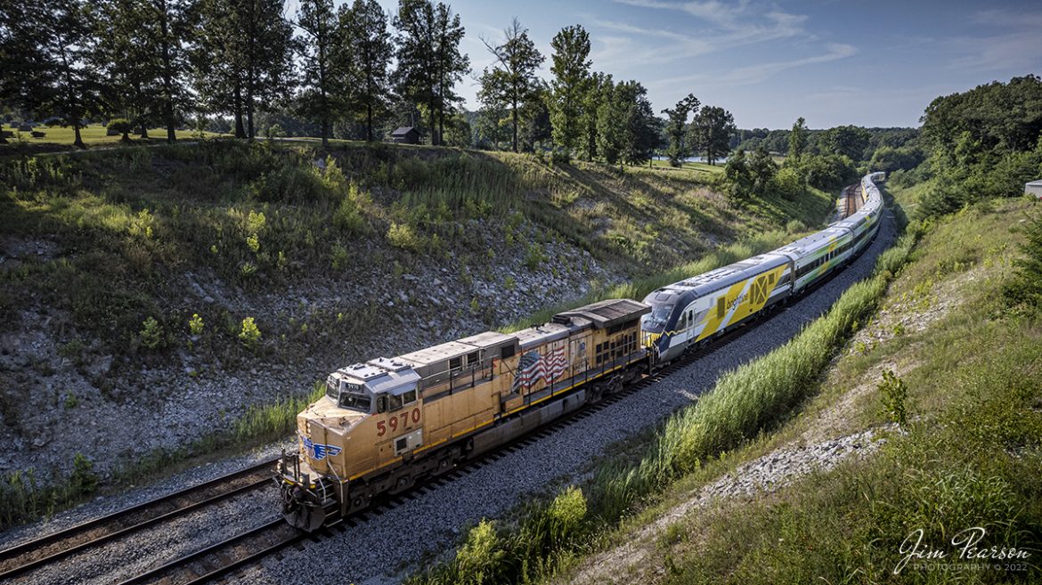 UP 5970 leads CSX S988 as it heads south through the S Curve at Nortonville, Kentucky with two new Brightline Green and Pink commuter train sets, as they head for Florida, on the Henderson Subdivision on July 16th, 2022.

These train sets were built by Siemens in Sacramento, California and are destined for service along Brightlines routes in Florida. 

According to Wikipedia: Brightline is a privately run intercity rail route between Miami and West Palm Beach, Florida that runs on track owned by Florida East Coast Railway. An extension from West Palm Beach to Orlando International Airport is expected to open in 2023.

Brightline is the only privately owned and operated intercity passenger railroad in the United States. Its development started in March 2012 as All Aboard Florida by Florida East Coast Industries; a Florida real estate developer owned by Fortress Investment Group. Construction began in November 2014 and the route opened in January 2018.

Tech Info: DJI Mavic Air 2S Drone, RAW, 22mm, f/2.8, 1/1250, ISO 100.

#trainphotography #railroadphotography #trains #railways #dronephotography #trainphotographer #railroadphotographer #jimpearsonphotography