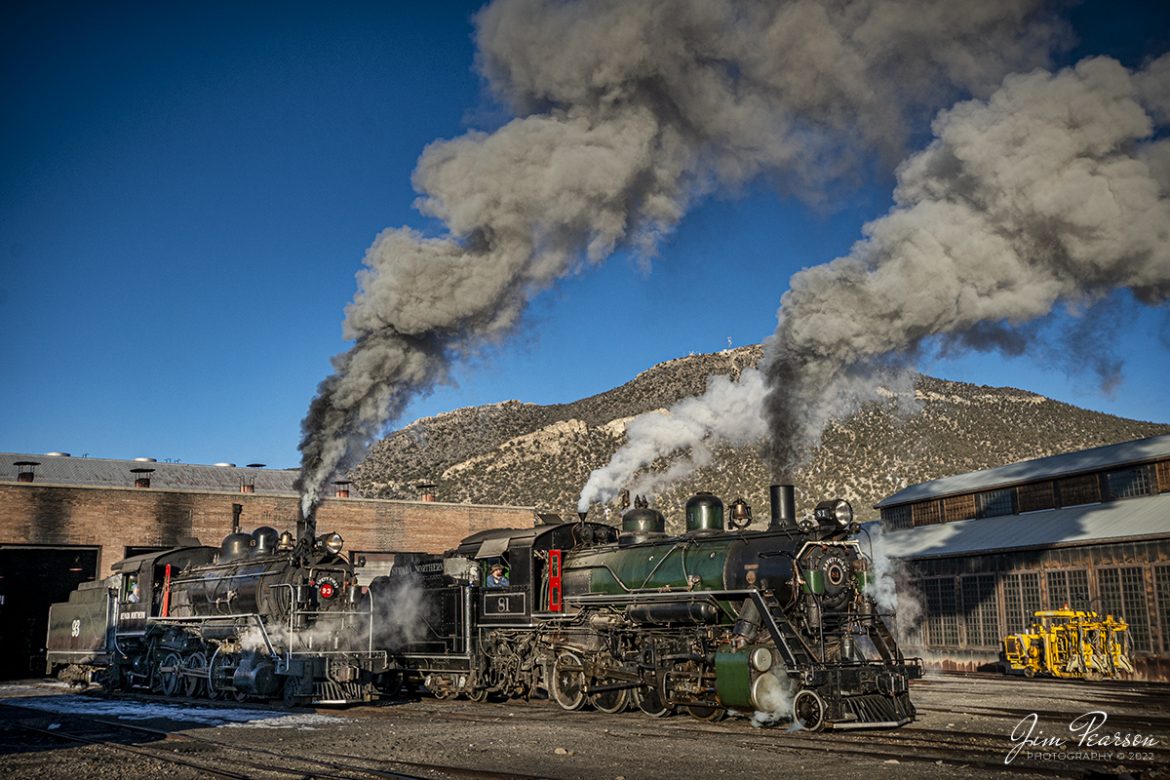 Early morning golden light rakes across the engine house as Nevada Northern Railway steam locomotives 93 and 81 pull out into the frigid air at Ely, Nevada, during the museums 2022 Winter Photo Charter event on February 12th, 2022.

According to Wikipedia: The Nevada Northern Railway Museum is a railroad museum and heritage railroad located in Ely, Nevada and operated by a historic foundation dedicated to the preservation of the Nevada Northern Railway.

The museum is situated at the East Ely Yards, which are part of the Nevada Northern Railway. The site is listed on the United States National Register of Historic Places as the Nevada Northern Railway East Ely Yards and Shops and is also known as the "Nevada Northern Railway Complex". The rail yards were designated a National Historic Landmark District on September 27, 2006. The site was cited as one of the best-preserved early 20th-century railroad yards in the nation, and a key component in the growth of the region's copper mining industry. Developed in the first decade of the 20th century, it served passengers and freight until 1983, when the Kennecott Copper Company, its then-owner, donated the yard to a local non-profit for preservation. The property came complete with all the company records of the Nevada Northern from its inception.

According to the NNRY website, #93 is a 2-8-0 that was built by the American Locomotive Company in January of 1909 at a cost of $17,610. It was the last steam locomotive to retire from original revenue service on the Nevada Northern Railway in 1961 and was restored back into service in 1993. 

Locomotive #81 is a "Consolidation" type (2-8-0) steam locomotive that was built for the Nevada Northern in 1917 by the Baldwin Locomotive Works in Philadelphia, PA, at a cost of $23,700. It was built for Mixed service to haul both freight and passenger trains on the Nevada Northern railway.

Tech Info: Nikon D800, RAW, Sigma 24-70 @ 24mm, f/8.1, 1/800, ISO 320.

#nevadanorthernrailway#trainphotography #railroadphotography #trains #railways #jimpearsonphotography #trainphotographer #railroadphotographer #jimpearsonphotography