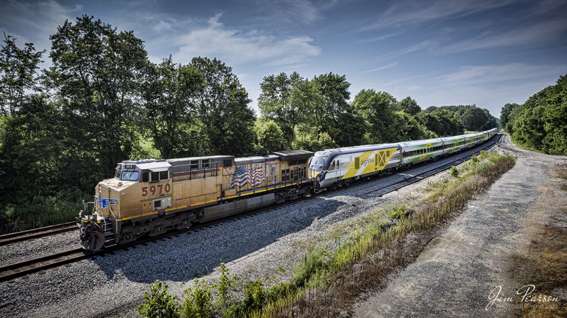 UP 5970 leads CSX S988 as it heads south at Anaconda at Robards, Kentucky with two new Brightline Green and Pink commuter train sets, as they head for Florida, on the Henderson Subdivision on July 16th, 2022.

These train sets were built by Siemens in Sacramento, California and are destined for service along Brightline’s routes in Florida. 

According to Wikipedia: Brightline is a privately run intercity rail route between Miami and West Palm Beach, Florida that runs on track owned by Florida East Coast Railway. An extension from West Palm Beach to Orlando International Airport is expected to open in 2023.

Brightline is the only privately owned and operated intercity passenger railroad in the United States. Its development started in March 2012 as All Aboard Florida by Florida East Coast Industries; a Florida real estate developer owned by Fortress Investment Group. Construction began in November 2014 and the route opened in January 2018.

Tech Info: DJI Mavic Air 2S Drone, RAW, 22mm, f/2.8, 1/2000 ISO 100.

#trainphotography #railroadphotography #trains #railways #dronephotography #trainphotographer #railroadphotographer #jimpearsonphotography