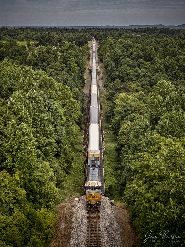 A southbound CSX I025 passes over Gum Lick Trestle, just north of Kelly, Kentucky on the Henderson Subdivision on September 2nd, 2022. This is cropped shot from my Air 2S Drone and shows the many autoracks running behind CSXT 3071 loaded with Teslas. I then moved the drone off the tracks before the train arrived at its location.

The Gum Lick name comes from the fact that the valley here is named Gum Lick Hollow and it sits between Crofton and Kelly Kentucky where it crosses over the West Fork of Pond River and is the highest and longest trestle on the CSX Henderson Subdivision. Its located between J. Knight Road grade crossing and the Cavanaugh Lane overpass.

This month this intermodal has been running with these autoracks loaded with Teslas out of California by way of Union Pacific on their way south to Florida. Todays train had 22 autoracks. The cars range in price from $46,000  $120,000, depending on the model. If you use the If you use a mid-range average price of $60,000 these 22 autoracks are carrying about $12 million dollars in Teslas!

Tech Info: DJI Mavic Air 2S Drone, RAW, 22mm, f/2.8, 1/1000, ISO 120.

#trainphotography #railroadphotography #trains #railways #dronephotography #trainphotographer #railroadphotographer #jimpearsonphotography