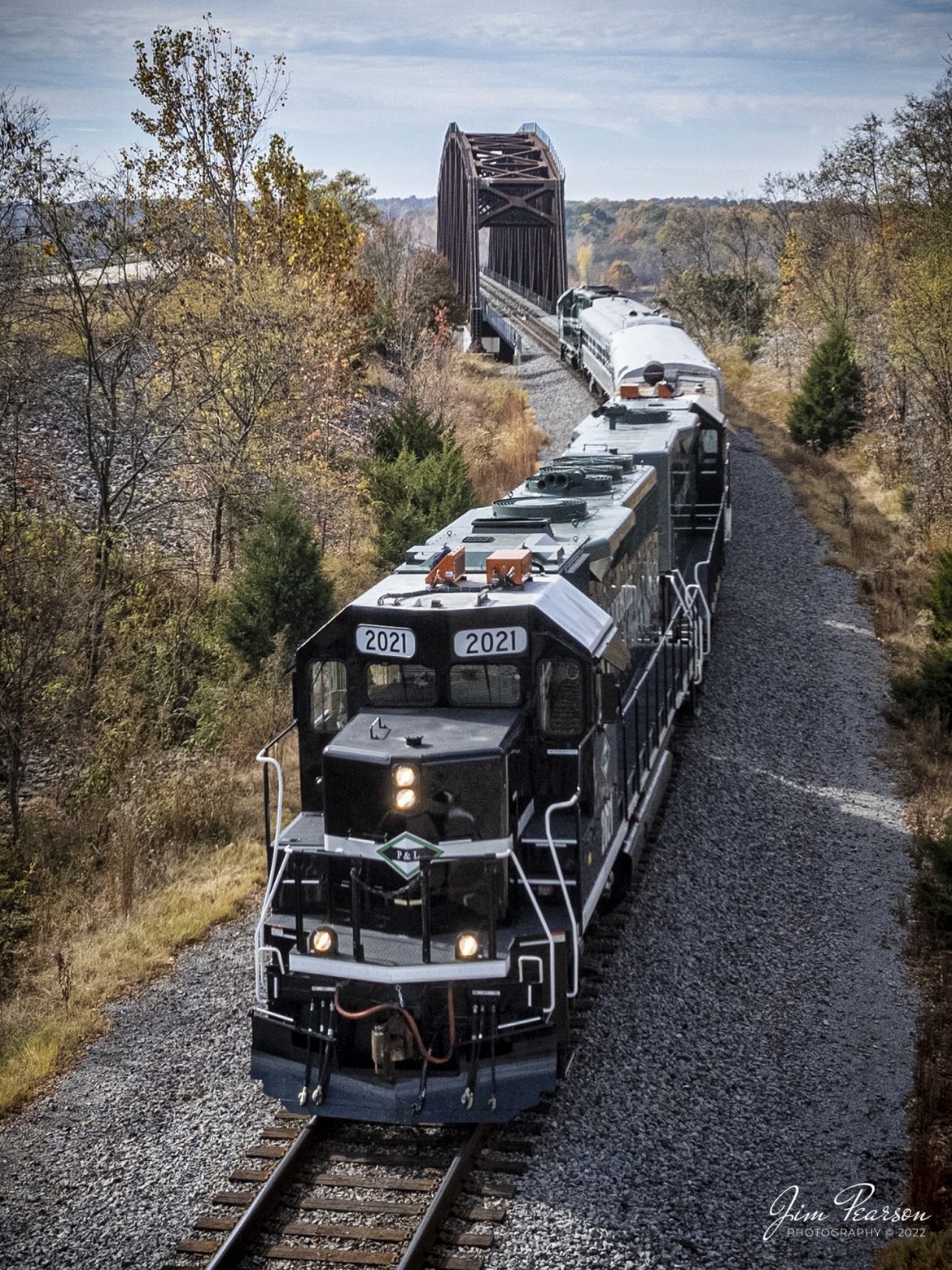 Saturday, October 29th, 2022, the Paducah and Louisville Railway (PAL) ran their Office Car Special (OCS) between Calvert City, Kentucky to just north of Barkley Dam to the railroad location known as Eureka, about 10 miles round trip. This event was in conjunction with their company picnic at Calvert City and the passengers were employees and their families. Here we catch them after they crossed the bridge over the Tennessee River at Kentucky Dam, north of Gilbertsville, Kentucky.

The consist was led by their 35th anniversary units PAL 2021 and 1986, followed by PAL 10, a generator car, built from an ex-L&N Milk Car that was manufactured in January 1958. Next was PAL II - lounge car or diner car from what I can find online, then PAL 1 "Bluegrass State I" business or lounge car, (ex-ICG 2, exx-IC 6, exxx-16). If anyone has more information on these cars, Id apricate your comments. The trailing engine is PAL 2127, Salute to our Troops locomotive, which led the train heading southbound to Calvert City, KY. 

Tech Info: DJI Mavic Air 2S Drone, 22mm, f/2.8, 1/2000, ISO 120.

#trainphotography #railroadphotography #trains #railways #dronephotography #trainphotographer #railroadphotographer #jimpearsonphotography #paducahandlouisvillerailway #pal #kentuckytrains