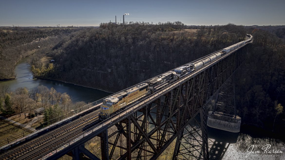 Union Pacific 4139 leads Norfolk Southern 196 across High Bridge on November 8th, 2022, as it heads north across the Kentucky River on the NS CNO&TP First District (Short Line).

According to Wikipedia: The High Bridge is a railroad bridge crossing the Kentucky River Palisades, that rises approximately 275 feet from the river below and connects Jessamine and Mercer counties in Kentucky. Formally dedicated in 1879, it is the first cantilever bridge constructed in the United States. It has a three-span continuous under-deck truss used by Norfolk Southern Railway to carry trains between Lexington and Danville. It has been designated as a National Historic Civil Engineering Landmark.

In 1851, the Lexington & Danville Railroad, with Julius Adams as chief engineer, retained John A. Roebling to build a railroad suspension bridge across the Kentucky River for a line connecting Lexington and Danville, Kentucky west of the intersection of the Dix and Kentucky rivers. In 1855, the company ran out of money and the project was resumed by Cincinnati Southern Railroad in 1873 following a proposal by C. Shaler Smith for a cantilever design using stone towers designed by John A. Roebling (who designed the Brooklyn Bridge).

The bridge was erected using a cantilever design with a three-span continuous under-deck truss and was opened in 1877 on the Cincinnati Southern Railway. It was 275 feet (84 m) tall and 1,125 feet (343 m) long: the tallest bridge above a navigable waterway in North America and the tallest railroad bridge in the world until the early 20th century. Construction was completed using 3,654,280 pounds of iron at a total cost of $404,373.31. In 1879 President Rutherford B. Hayes and Gen. William Tecumseh Sherman attended the dedication.

After years of heavy railroad use, the bridge was rebuilt by Gustav Lindenthal in 1911. Lindenthal reinforced the foundations and rebuilt the bridge around the original structure. To keep railroad traffic flowing, the track deck was raised by 30 feet during construction and a temporary trestle was constructed.[6] In 1929, an additional set of tracks was built to accommodate increased railroad traffic and the original limestone towers were removed.

Tech Info: DJI Mavic Air 2S Drone, 22mm, f/2.8, 1/2000, ISO 110.

#trainphotography #railroadphotography #trains #railways #dronephotography #trainphotographer #railroadphotographer #jimpearsonphotography #trainsfromtheair #trainsfromadrone