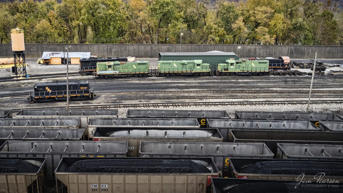 A variety of Kanawha River Terminal Railroad locomotives sit just outside the engine house in the yards at the Kanawha River Terminal (Ceredo Dock) at Ceredo, West Virginia, on November 2nd, 2022. From what I can tell, from the left is #698, 455 (high nose green) 894 & 994. Cant read numbers on the back units behind them. 

According to their website: The Kanawha River Terminal Railroad is a switching operation serving the Kanawha River Terminal (Ceredo Dock) facility, situated along the Ohio River west of Huntington, West Virginia. The railroad operation handles interchange with Norfolk Southern and CSX Transportation. 

The terminal has an annual throughput capacity of nearly 20 million tons and is equipped with a rotary dumper and a barge loader, the latter of which provides volume coal loading to barges. The facility and the switching railroad are owned by SunCoke Energy. A variety of first and second-generation motive power is maintained at an engine house in Ceredo, West Virginia, adjacent to the terminal.

Tech Info: DJI Mavic Air 2S Drone, 22mm, f/2.8, 1/500, ISO 150.

#trainphotography #railroadphotography #trains #railways #dronephotography #trainphotographer #railroadphotographer #jimpearsonphotography #trainsfromtheair
