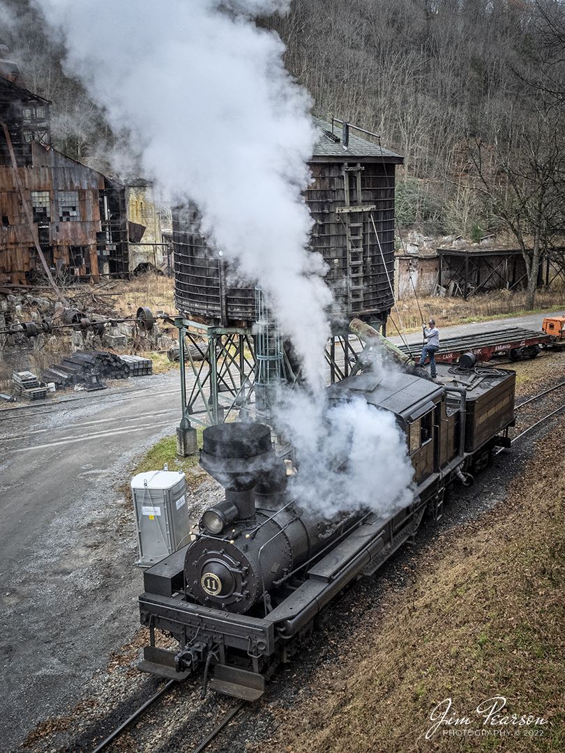 The fireman stands on the tender of Cass Scenic Railway Shay locomotive number 11, (C-90-3) as they take on water during the Rail Heritage Photography Weekend photo shoot at Cass, West Virginia on November 5th, 2022. 

According to Wikipedia: Cass Scenic Railroad, is an 11-mile (18 km) long heritage railway owned by the West Virginia State Rail Authority and operated by the Durbin and Greenbrier Valley Railroad. The park also includes the former company town of Cass and a portion of the summit of Bald Knob, the highest point on Back Allegheny Mountain.

Founded in 1901 by the West Virginia Pulp and Paper Company (now WestRock), Cass was built as a company town to serve the needs of the men who worked in the nearby mountains cutting spruce and hemlock for the West Virginia Spruce Lumber Company, a subsidiary of WVP&P. At one time, the sawmill at Cass was the largest double-band sawmill in the world. It processed an estimated 1.25 billion board feet (104,000,000 cu ft; 2,950,000 m3) of lumber during its lifetime. In 1901 work started on the 4 ft 8+1⁄2 in (1,435 mm) standard gauge railroad, which climbs Back Allegheny Mountain. 

The railroad eventually reached a meadow area, now known as Whittaker Station, where a logging camp was established for the immigrants who were building the railroad. The railroad soon reached the top of Gobblers Knob, and then a location on top of the mountain known as 'Spruce'. The railroad built a small town at that location, complete with a company store, houses, a hotel, and a doctor's office. Work soon commenced on logging the red spruce trees, which grew in the higher elevations.

Tech Info: DJI Mavic Air 2S Drone, 22mm, f/2.8, 1/350, ISO 200.

#trainphotography #railroadphotography #trains #railways #dronephotography #trainphotographer #railroadphotographer #jimpearsonphotography #cassscenicrailway #durbinandgreenbriervalleyrr #trainsfromtheair#steamtrains