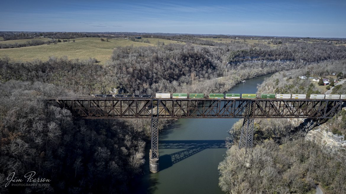 A southbound Norfolk Southern intermodal heads across High Bridge on November 8th, 2022, as it heads north across the Kentucky River on the NS CNO&TP First District at Highbridge, Kentucky.

According to Wikipedia: The High Bridge is a railroad bridge crossing the Kentucky River Palisades, that rises approximately 275 feet from the river below and connects Jessamine and Mercer counties in Kentucky. Formally dedicated in 1879, it is the first cantilever bridge constructed in the United States. It has a three-span continuous under-deck truss used by Norfolk Southern Railway to carry trains between Lexington and Danville. It has been designated as a National Historic Civil Engineering Landmark.

In 1851, the Lexington & Danville Railroad, with Julius Adams as chief engineer, retained John A. Roebling to build a railroad suspension bridge across the Kentucky River for a line connecting Lexington and Danville, Kentucky west of the intersection of the Dix and Kentucky rivers. In 1855, the company ran out of money and the project was resumed by Cincinnati Southern Railroad in 1873 following a proposal by C. Shaler Smith for a cantilever design using stone towers designed by John A. Roebling (who designed the Brooklyn Bridge).

The bridge was erected using a cantilever design with a three-span continuous under-deck truss and was opened in 1877 on the Cincinnati Southern Railway. It was 275 feet (84 m) tall and 1,125 feet (343 m) long: the tallest bridge above a navigable waterway in North America and the tallest railroad bridge in the world until the early 20th century. Construction was completed using 3,654,280 pounds of iron at a total cost of $404,373.31. In 1879 President Rutherford B. Hayes and Gen. William Tecumseh Sherman attended the dedication.

After years of heavy railroad use, the bridge was rebuilt by Gustav Lindenthal in 1911. Lindenthal reinforced the foundations and rebuilt the bridge around the original structure. To keep railroad traffic flowing, the track deck was raised by 30 feet during construction and a temporary trestle was constructed.[6] In 1929, an additional set of tracks was built to accommodate increased railroad traffic and the original limestone towers were removed.

Tech Info: DJI Mavic Air 2S Drone, 22mm, f/2.8, 1/1600, ISO 120.

#trainphotography #railroadphotography #trains #railways #dronephotography #trainphotographer #railroadphotographer #jimpearsonphotography #trainsfromtheair