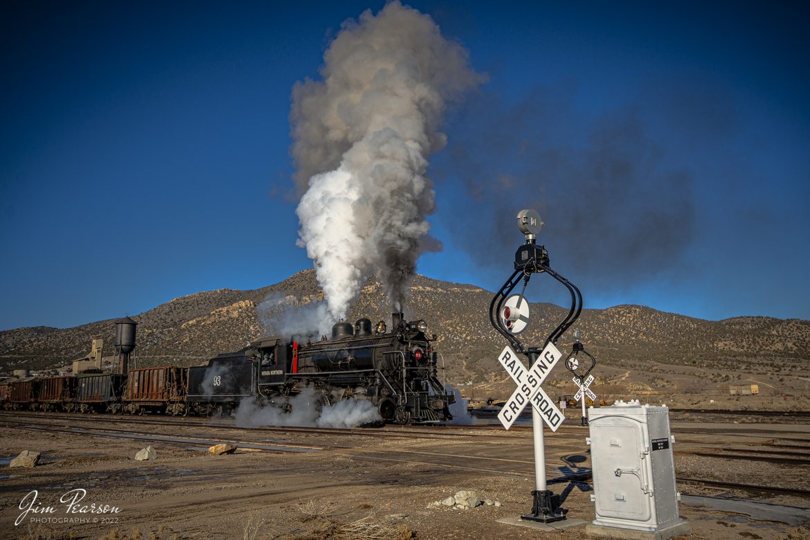 With the wigwag signals swinging, Nevada Northern Railway steam locomotive 93 begins to pull a string of ore cars through a crossing at Ely, Nevada, during the museums 2022 Winter Photo Charter event on February 12th, 2022.

According to Wikipedia: The Nevada Northern Railway Museum is a railroad museum and heritage railroad located in Ely, Nevada and operated by a historic foundation dedicated to the preservation of the Nevada Northern Railway.

Wigwag is a nickname for a type of railroad grade crossing signal once common in North America, referring to its pendulum-like motion that signaled the approach of a train. The device is generally credited to Albert Hunt, a mechanical engineer at Southern California's Pacific Electric (PE) interurban streetcar railroad, who invented it in 1909 for safer railroad grade crossings. The term should not be confused with its usage in Britain, where "wigwag" generally refers to alternate flashing lights, such as those found at modern level crossings.

According to the NNRY website, #93 is a 2-8-0 that was built by the American Locomotive Company in January of 1909 at a cost of $17,610. It was the last steam locomotive to retire from original revenue service on the Nevada Northern Railway in 1961 and was restored back into service in 1993. 

Tech Info: Nikon D800, RAW, Sigma 24-70 @ 19mm, f/7.1, 1/800, ISO 110.

#nevadanorthernrailway#trainphotography #railroadphotography #trains #railways #jimpearsonphotography #trainphotographer #railroadphotographer #jimpearsonphotography