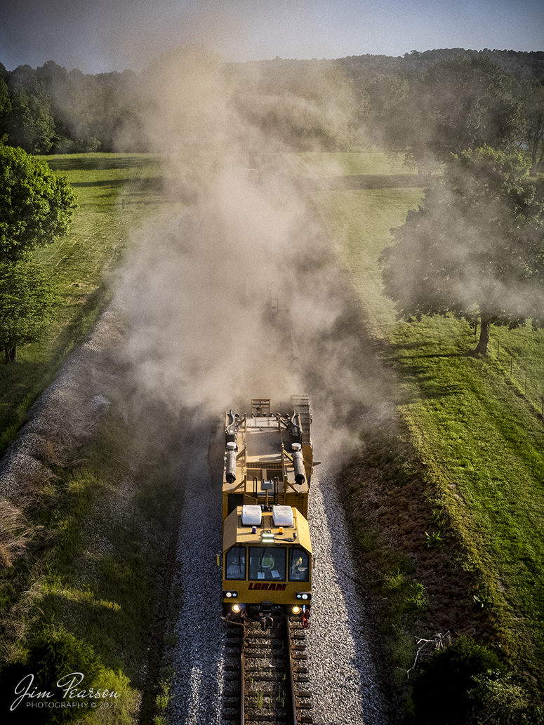 LoRam shoulder ballast cleaner SBC-2401 kicks up a dust storm as it makes its way north on the CSX Henderson Cuttoff through the beautiful spring countryside of Mortons Gap, Kentucky on May 10th, 2022, as it moves slowly along cleaning the ballast on both sides of the rails.

Shoulder ballast cleaning consists of removing ballast at the end of the ties, screening the ballast, and discarding fines and fouling material and restoring the good ballast to the shoulder. Integrated scarifiers break open end of tie mud pockets, removes fines, and restores ballast voids in the shoulders and under the tie ends and release damaging trapped water.

Tech Info: DJI Mavic Air 2S Drone, RAW, 22mm, f/2.8, 1/1600, ISO 130.

#trainphotography #railroadphotography #trains #railways #dronephotography #trainphotographer #railroadphotographer #jimpearsonphotography #trainsfromtheair #trainsfromadrone
