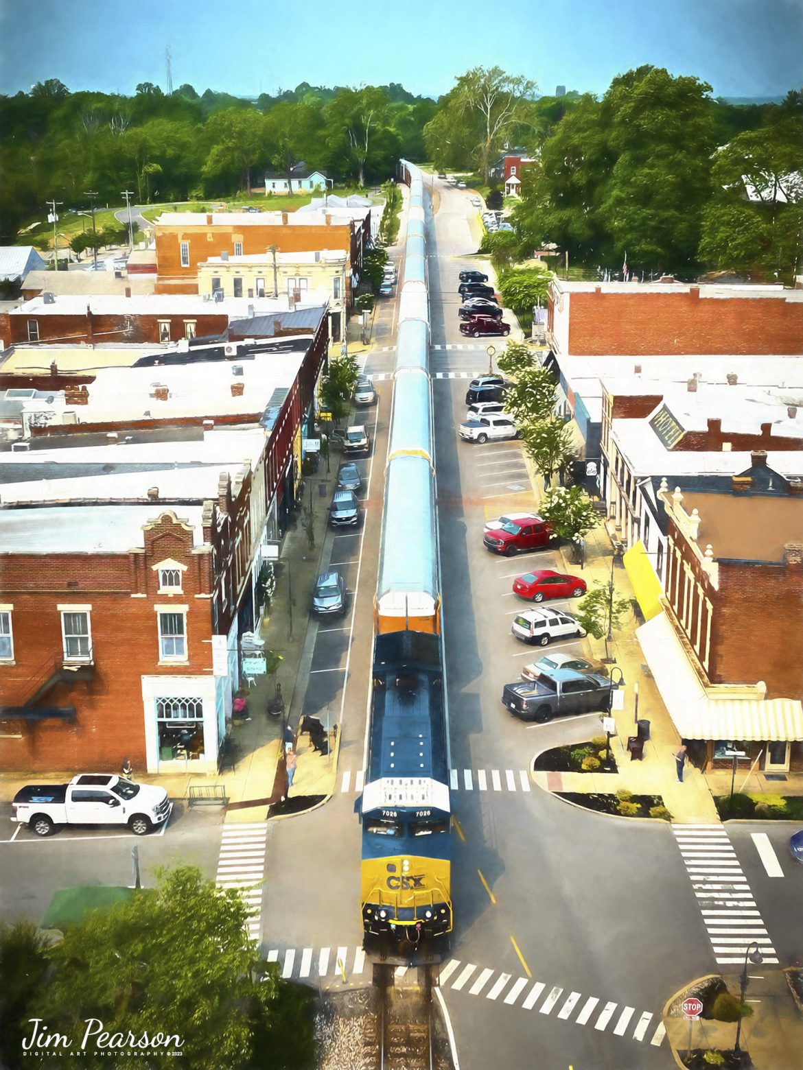 CSXT 7026 leads CSX M352, a loaded autorack train as they street run through downtown LaGrange, Kentucky, headed north on the LCL Subdivision on May 17th, 2023.

According to the Train Aficionado website: CSX runs through La Grange on what is known as the LCL Subdivision. This 101-mile line connects Covington, Kentucky, to Louisville, Kentucky. The railroad tracks run right through the heart of the town literally. The railroad tracks are embedded on the eastbound side of the roadway for the whole stretch of downtown. The trains pass the city business district which includes quaint shops and restaurants. When looking up railfanning in La Grange most websites state anywhere from 14 to 20 trains travel through here daily.

According to Hidden History of La Grange, Ky by author and local historian Nancy Stearns, LaGrange is known for its trains. It became an important junction for the railroad, with lines going to Frankfort and Cincinnati, and this made the town an important stop for travelers and businesses. The interurban electric rail car made round trips from LaGrange to Louisville daily until automobiles surpassed the interurban in popularity.

Tech Info: DJI Mavic 3 Classic Drone, RAW, 24mm, f/2.8, 1/1250, ISO 100.

#trainphotography #railroadphotography #trains #railways #dronephotography #trainphotographer #railroadphotographer #jimpearsonphotography #CSXtrains #mavic3classic #drones #trainsfromtheair #trainsfromadrone #emptycoaltrain #autoracktrain #kentuckytrains #LaGrangeKy #streetrunningtrains