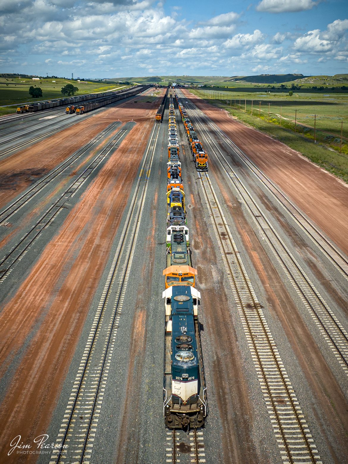 On June 28th, 2023, I tried to count the locomotives stored on the Black Hills Subdivision at the BNSF Donkey Creek Yard at Rozet, Wyoming in the two lines of locomotives from this picture, but theres too many and seem to go on forever. The trains on the far left are coal trains, loaded and empty, waiting on crews.

According to news reports I found online, this yard was scheduled to close June 5th, 2022, affecting 38 jobs, but from what I could see there were people working in the yard, so Im not sure if that happened or not. The reported layoff was due to the tough market for coal. It has been a bit over a year and perhaps things have changed since then.

Tech Info: DJI Mavic 3 Classic Drone, RAW, 24mm, f/2.8, 1/1600, ISO 100.

#trainphotography #railroadphotography #trains #railways #dronephotography #trainphotographer #railroadphotographer #jimpearsonphotography #trains #mavic3classic #drones #trainsfromtheair #trainsfromadrone #BNSF