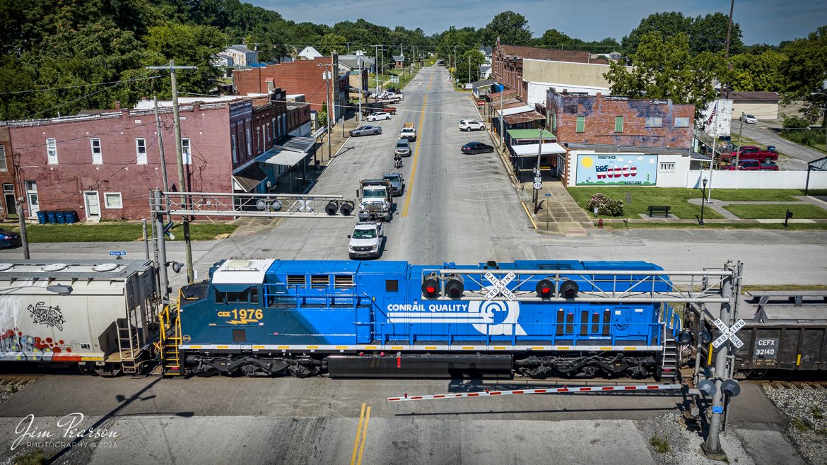 The newly released CSX Heritage series locomotive, 1976, Conrail Quality unit, passes through the crossing in downtown Sebree, Kentucky, on CSX M513 south, as it heads down the Henderson Subdivision as the DPU, on July 31st, 2023.

According to Wikipedia: Conrail (reporting mark CR), formally the Consolidated Rail Corporation, was the primary Class I railroad in the Northeastern United States between 1976 and 1999. The trade name Conrail is a portmanteau based on the company's legal name. It continues to do business as an asset management and network services provider in three Shared Assets Areas that were excluded from the division of its operations during its acquisition by CSX Corporation and the Norfolk Southern Railway.

The federal government created Conrail to take over the potentially profitable lines of multiple bankrupt carriers, including the Penn Central Transportation Company and Erie Lackawanna Railway. After railroad regulations were lifted by the 4R Act and the Staggers Act, Conrail began to turn a profit in the 1980s and was privatized in 1987. The two remaining Class I railroads in the East, CSX Transportation and the Norfolk Southern Railway (NS), agreed in 1997 to acquire the system and split it into two roughly equal parts (alongside three residual shared-assets areas), returning rail freight competition to the Northeast by essentially undoing the 1968 merger of the Pennsylvania Railroad and New York Central Railroad that created Penn Central. Following approval by the Surface Transportation Board, CSX and NS took control in August 1998, and on June 1, 1999, began operating their respective portions of Conrail.

Tech Info: DJI Mavic 3 Classic Drone, RAW, 24mm, f/2.8, 1/2000, ISO 120.

#trainphotography #railroadphotography #trains #railways #dronephotography #trainphotographer #railroadphotographer #jimpearsonphotography #trains #csxt #mavic3classic #drones #trainsfromtheair #trainsfromadrone #CSXHeritageUnits