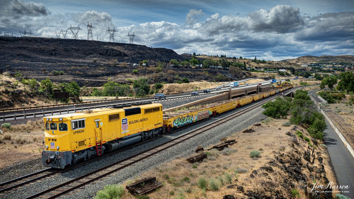 During our run to Seattle, Washington my sister and I traveled along the Columbia River Gorge on our recent trip and the only Union Pacific Equipment I caught on this day was this Maintenance of Way Equipment at The Dalles in Oregon. It was busy picking up ties on the Portland Subdivision,down from The Dalles Dam, on June 20th, 2023, with UP 958200 leading. 

At the far end of the equipment, you can see where they are picking up ties along the right-of-way and I’ll be posting another shot showing that end tomorrow morning. An unusual and cool looking piece of equipment for sure!

From what I can find online Union Pacific took delivery of the RELCO built MofW work train set #958200 in July 2019. The set is made up of special flats/gons and a rebuilt SD-40-2 locomotive (former number unknown). The trailing unit was numbered UP 958201.

Tech Info: DJI Mavic 3 Classic Drone, RAW, 24mm, f/2.8, 1/3200, ISO 180

#trainphotography #railroadphotography #trains #railways #dronephotography #trainphotographer #railroadphotographer #jimpearsonphotography #trains #mavic3classic #drones #trainsfromtheair #trainsfromadrone #UnionPacific #MOWtrainset #oregontrains