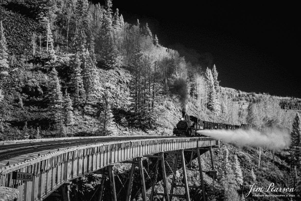 In this week’s Saturday Infrared photo, we find Cumbres & Toltec Scenic Railroad steam locomotive 463 as it conducts a boiler blowdown as it leads a freight over the Cascade Trestle as it heads west, out of Antonito, Colorado, during a photo charter by Dak Dillon Photography on October 19th, 2023.

A blowdown is a way to get minerals and other contaminants out of the locomotive system. Engines want to be on a bridge or trestle because the blow down itself can reach 30+ feet at an angle away from the firebox with live steam. 

According to their website: the Cumbres & Toltec Scenic Railroad is a National Historic Landmark.  At 64-miles in length, it is the longest, the highest and most authentic steam railroad in North America, traveling through some of the most spectacular scenery in the Rocky Mountain West.

Owned by the states of Colorado and New Mexico, the train crosses state borders 11 times, zigzagging along canyon walls, burrowing through two tunnels, and steaming over 137-foot Cascade Trestle. All trains steam along through deep forests of aspens and evergreens, across high plains filled with wildflowers, and through a rocky gorge of remarkable geologic formations. Deer, antelope, elk, fox, eagles and even bear are frequently spotted on this family friendly, off-the grid adventure.

Tech Info: Fuji XT-1, RAW, Converted to 720nm B&W IR, Sigma 24-70 @ 24mm, f/5.6, 1/420, ISO 400.

#trainphotography #railroadphotography #trains #railways #jimpearsonphotography #infraredtrainphotography #infraredphotography #trainphotographer #railroadphotographer #CumbresandToltecScenicRailroad #steamtrain