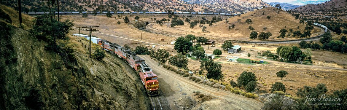 Santa Fe Railway 142 leads four war bonnets as they pull east through Tehachapi Loop with a “Piggyback” trailer train sometime in the late 1980’s, as they head for Tehachapi, California, and points east on the UP Mojave Subdivision, through the Tehachapi Pass.

When I lived in southern California between 1981-1995, not counting a break where I lived in the Philippines for about 1.5 years, I spent a lot of time in these mountains and Cajon Pass, around the San Bernardino mountains! Over the coming year I’ll be scanning images from these and other locations and sharing them on Saturday evenings.

According to Wikipedia: The Tehachapi Loop is a 3,779-foot-long (0.72 mi; 1.15 km) spiral,[1] or helix, on the Union Pacific Railroad Mojave Subdivision through Tehachapi Pass, of the Tehachapi Mountains in Kern County, south-central California. The line connects Bakersfield and the San Joaquin Valley to Mojave in the Mojave Desert.

Rising at a steady two-percent grade, the track gains 77 feet (23 m) in elevation and makes a 1,210-foot-diameter (370 m) circle.[1][2] Any train that is more than 3,800 feet (1,200 m) long—about 56 boxcars—passes over itself going around the loop

Fuji 6x17, Fuji 105mm lens, other exposure information wasn’t recorded back then.

#trainphotography #railroadphotography #trains #railways #jimpearsonphotography #panphotography #6x17photography #trainphotographer #railroadphotographer #TehachapiLoop #SantaFe