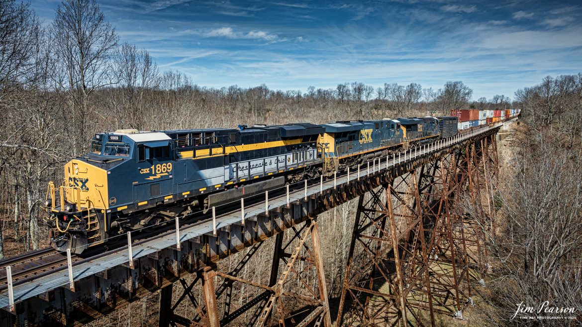 CSX Chesapeake & Ohio Heritage unit 1869 leads hot intermodal, CSX I025, across Gum Lick Trestle as it head south, just north of Kelly, Kentucky on the Henderson Subdivision on February 29th, 2024.

According to the CSX Website: A locomotive commemorating the proud history of the Chesapeake and Ohio Railway has entered service as the fifth in the CSX heritage series celebrating the lines that came together to form the modern railroad.

Numbered CSX 1869 in honor of the year the C&O was formed in Virginia from several smaller railroads, the newest heritage locomotive sports a custom paint design that includes today’s CSX colors on the front of the engine and transitions to a paint scheme inspired by 1960s era C&O locomotives on the rear two-thirds.

The C&O Railway was a major line among North American freight and passenger railroads for nearly a century before becoming part of the Chessie System in 1972 and eventually merging into the modern CSX. In 1970, the C&O included more than 5,000 route miles of track stretching from Newport News, Virginia, to Chicago and the Great Lakes.

Designed and painted at CSXs locomotive shop in Waycross, Georgia, the C&O unit will join four other commemorative units in revenue service on CSXs 20,000-mile rail network.

The heritage series is reinforcing employee pride in the history of the railroad that continues to move the nation’s economy with safe, reliable, and sustainable rail-based transportation services.

Tech Info: DJI Mavic 3 Classic Drone, RAW, 22mm, f/2.8, 1/2500, ISO 140.

#trainphotography #railroadphotography #trains #railways #jimpearsonphotography #trainphotographer #railroadphotographer #csxt #dronephoto #trainsfromadrone #trending #CSXHeritageUnit