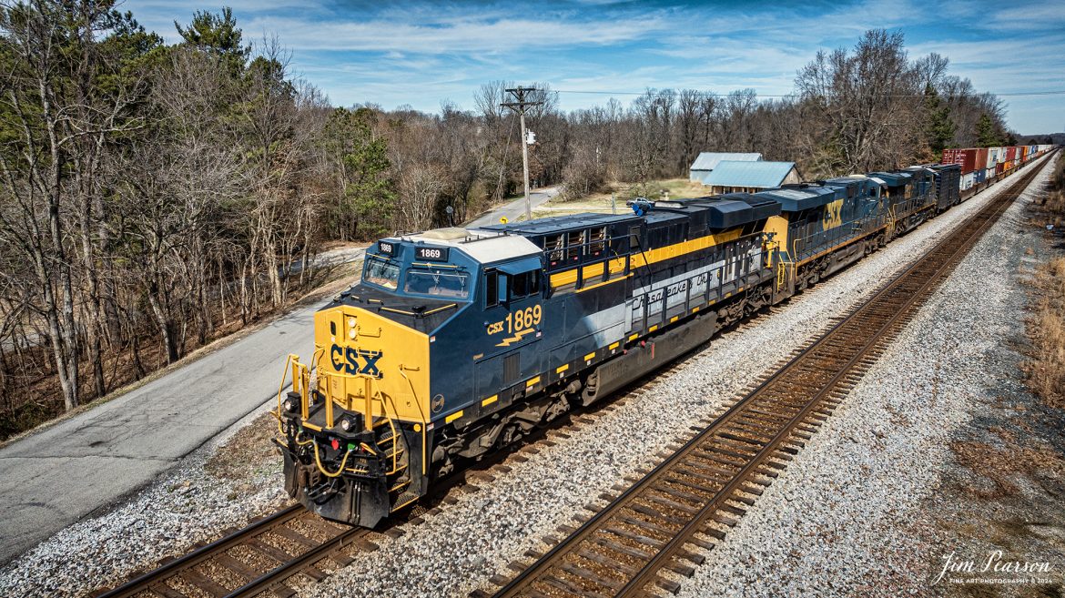 CSX Chesapeake & Ohio Heritage unit 1869 leads hot intermodal, CSX I025, as it approaches the south end of the siding at Slaughters, Kentucky as it heads south on the Henderson Subdivision on February 29th, 2024.

According to the CSX Website: A locomotive commemorating the proud history of the Chesapeake and Ohio Railway has entered service as the fifth in the CSX heritage series celebrating the lines that came together to form the modern railroad.

Numbered CSX 1869 in honor of the year the C&O was formed in Virginia from several smaller railroads, the newest heritage locomotive sports a custom paint design that includes today’s CSX colors on the front of the engine and transitions to a paint scheme inspired by 1960s era C&O locomotives on the rear two-thirds.

The C&O Railway was a major line among North American freight and passenger railroads for nearly a century before becoming part of the Chessie System in 1972 and eventually merging into the modern CSX. In 1970, the C&O included more than 5,000 route miles of track stretching from Newport News, Virginia, to Chicago and the Great Lakes.

Designed and painted at CSX’s locomotive shop in Waycross, Georgia, the C&O unit will join four other commemorative units in revenue service on CSX’s 20,000-mile rail network.

The heritage series is reinforcing employee pride in the history of the railroad that continues to move the nation’s economy with safe, reliable, and sustainable rail-based transportation services.

Tech Info: DJI Mavic 3 Classic Drone, RAW, 22mm, f/2.8, 1/2000, ISO 110.

#trainphotography #railroadphotography #trains #railways #jimpearsonphotography #trainphotographer #railroadphotographer #csxt #dronephoto #trainsfromadrone #trending #CSXHeritageUnit