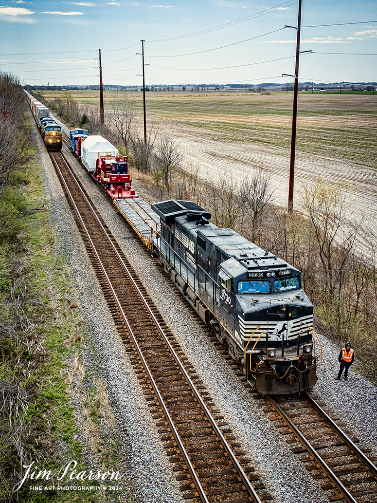 The conductor on Norfolk Southern 3730 CSX S991 with an oversized Turbine load from Siemens Energy on a depressed flatbed prepares to do a roll-by inspection as they wait for CSX I128 to pass them toward the north end of King, at Princeton, Indiana, on the CSX CE&D Subdivision, on March 20th, 2024, with a Fracht Caboose bringing up the rear. 

B229 originated at Birmingham, AL and is headed for New Castle, PA. I caught this move just north of Evansville, IN and gave chase to Patoka, Indiana. 

Tech Info: DJI Mavic 3 Classic Drone, RAW, 22mm, f/2.8, 1/2500, ISO 260.

#trainphotography #railroadphotography #trains #railways #jimpearsonphotography #trainphotographer #railroadphotographer #csxt #dronephoto #trainsfromadrone #trending #csxcedsubdivision #norfolksouthern #trending
