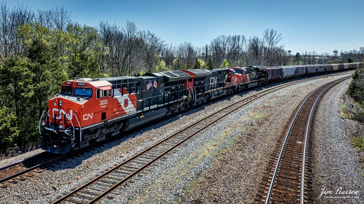 Canadian National (CN) locomotive 3233 (Support our Troops) leads B229-13 as they wait for hot intermodal I025 to pass them at Arklow, at Madisonville, Kentucky, on the CSX Henderson Subdivision, March 16th, 2024, so they can continue their move north.

From a CN Press Release: “CN’s two tribute locomotives (CN 3233 & 3015) pay homage to veterans and active military men and women across North America. Their custom design represents the proud footprint we have established across our network and our deep recognition for the veterans who live and work in the communities our trains pass through every day. 

Tech Info: DJI Mavic 3 Classic Drone, RAW, 22mm, f/2.8, 1/2500, ISO 180.

#trainphotography #railroadphotography #trains #railways #jimpearsonphotography #trainphotographer #railroadphotographer #csxt #dronephoto #trainsfromadrone #trending #csxhendersonsubdivision #cnrailway