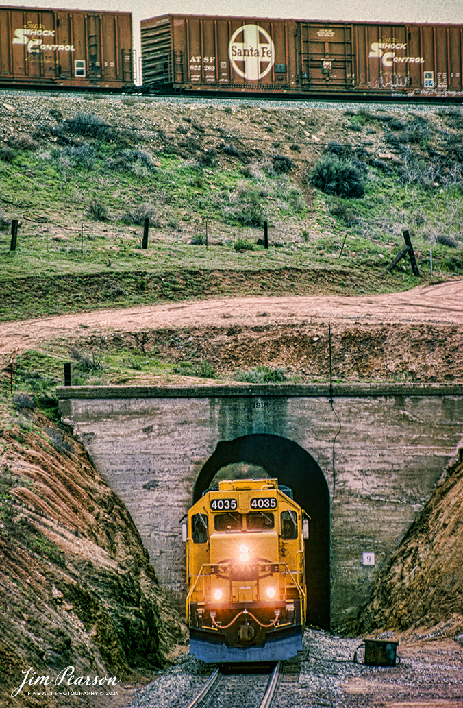 Santa Fe 4035 passes through tunnel 9 under their train above in the Tehachapi Loop as they begin to pull through the loop on their way west on the UP Mojave Subdivision in April of 1995.

According to Wikipedia: The Tehachapi Loop is a 3,779-foot-long (0.72 mi; 1.15 km) spiral, or helix, on the Union Pacific Railroad Mojave Subdivision through Tehachapi Pass, of the Tehachapi Mountains in Kern County, south-central California. The line connects Bakersfield and the San Joaquin Valley to Mojave in the Mojave Desert.

Rising at a steady two-percent grade, the track gains 77 feet (23 m) in elevation and makes a 1,210-foot-diameter (370 m) circle. Any train that is more than 3,800 feet (1,200 m) long—about 56 boxcars—passes over itself going around the loop. At the bottom of the loop, the track passes through Tunnel 9, the ninth tunnel built as the railroad was extended from Bakersfield, CA.

The line averages about 36 freight trains each day. Passenger trains such as Amtrak's San Joaquin are banned from the loop, although the Coast Starlight can use it as a detour. Its frequent trains and scenic setting make the Tehachapi Loop popular with railfans. In 1998, it was named a National Historic Civil Engineering Landmark. It is also designated as California Historical Landmark #508.

Tech Notes: Nikon F3 Film Camera, Nikon 70-300mm lens at 300mm, f/stop and shutter speed not recorded