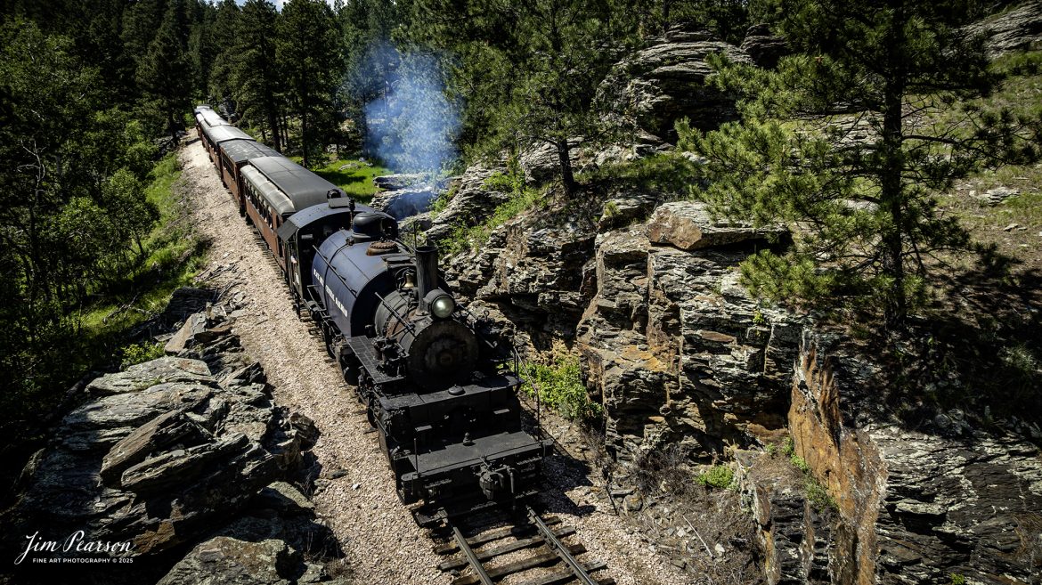 The Black Hills Central Railway locomotive 108 works their way through one of many rock cuts through the Black Hills countryside as it makes its third trip of the day between Hill City to Keystone, South Dakota, on June 26th, 2025. A big shout out to Cory Jakeway for all the help on finding my way around on the railroad and railfanning with me!

According to their website: Locomotive is a 2-6-6-2T articulated tank engine that was built by the Baldwin Locomotives Works in 1926 for the Potlatch Lumber Company. It later made its way to Weyerhaeuser Timber Company and eventually to the Northwest Railway Museum in Snoqualmie, Washington.

The acquisition and subsequent restoration of locomotive 108 completed a more than 20-year goal of increasing passenger capacity which began with the restoration of 110 and the restoration of multiple passenger cars. Both large Mallet locomotives (pronounced “Malley”) can pull a full train of seven authentically restored passenger cars, up from the four cars utilized prior to their addition to the roster.

Tech Info: DJI Mavic 3 Classic Drone, RAW, 24mm, f/2.8, 1/2000, ISO 100.

#railroad #railroads #train, #trains #railway #railway #steamtrains #railtransport #railroadengines #picturesoftrains #picturesofrailways #besttrainphotograph #bestphoto #photographyoftrains #bestsoldpicture #JimPearsonPhotography #trainsfromtheair #trainsfromadrone #1880train #steamtrain #blackhills