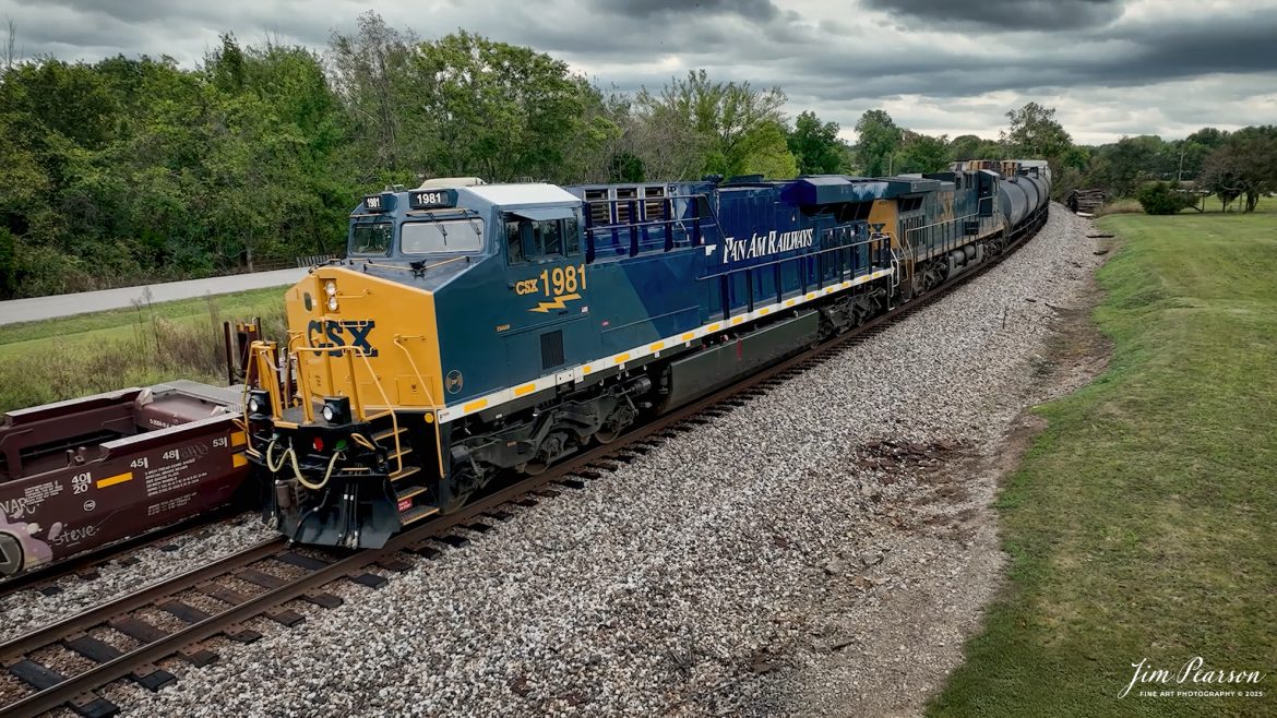 CSXT 1981 Pan Am Railways Heritage Unit leads M512 as they wait for SB I025 to pass them via the siding at Kelly, Kentucky, on September 24th, 2025, on the CSX Henderson Subdivision.

According to a CSXT Press Release: November 25, 2024 – CSX has unveiled locomotive No. 1981, the final installment in its series of heritage locomotives, honoring Pan Am Railways. The unit is the 21st and final creation by the Waycross Paint Shop to celebrate the predecessor railroads that form today’s CSX network.

Pan Am Railways, formerly known as Guilford Transportation, was established in 1981 and operated across northern New England, spanning from Maine to New York. It joined the CSX family in 2022 following a purchase agreement.

The heritage series required extra care and precision, according to CSX carman painter Albert Bussey. “It’s always special working on the heritage units,” Bussey said. “Like always, we try to take a little bit of extra care and time in order to do these perfectly.”

All 21 heritage units are not just displays of craftsmanship but active locomotives performing daily duties throughout CSX’s 26-state rail network. The dedication behind their creation reflects the artistry of the team at the Waycross Paint Shop.

The completion of locomotive No. 1981 stands as a tribute to the history of Pan Am Railways and the pride shared by CSX employees. As CSX approaches its 200th anniversary in 2027, these heritage locomotives symbolize the company’s enduring legacy and its dedication to innovation and service.

Tech Info: 4K Frame Grab from a DJI Mavic 3 Classic Drone, RAW, 22mm, f/2.8.

#railroad #railroads #train, #trains #railway #railway #steamtrains #railtransport #railroadengines #picturesoftrains #picturesofrailways #besttrainphotograph #bestphoto #photographyoftrains #bestsoldpicture #JimPearsonPhotography #trainsfromtheair #trainsfromadrone #onecsx #csx
