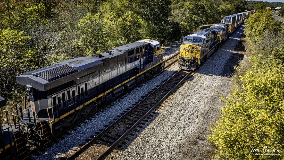 CSXT 1834 Georgia Railroad Heritage Unit leads E904 as they wait on the main for southbound I195 to clear the north end of Slaughters, Kentucky, on October 14th, 2025, on the CSX Henderson Subdivision. 

I thought capturing this unit had finished up my goal of capturing all the current CSX Heritage Units but looking over my records I still have yet to capture the 1902 Clinchfield locomotive and so the hunt continues!

According to a CSXT Press Release: June 27, 2024 - CSX has unveiled a new heritage locomotive honoring the legacy of the Georgia Railroad. This initiative is part of CSX's ongoing efforts to recognize and pay tribute to the historic railroads that have played a pivotal role in shaping the American railway system.

The Georgia Railroad, also known as the Georgia Railroad and Banking Company, was chartered in 1833 and became one of the earliest and most influential railroads in the southeastern United States. Headquartered in Augusta, Georgia, the railroad was instrumental in facilitating transport and commerce across the region during the 19th and early 20th centuries.

Originally, the Georgia Railroad was established to connect Augusta with Athens, Georgia. Its route expanded over time, linking key cities such as Atlanta and Macon, thereby becoming an important artery for economic growth in the state. The railroad was renowned for its efficiency and reliability, transporting both passengers and freight.

In addition to its transportation services, the Georgia Railroad also had substantial banking operations, which further cemented its role as a vital institution in the region. Throughout its operational years, it underwent several mergers and partnerships, maintaining its prominence in the railway industry until it eventually became part of the CSX network.

CSX's heritage locomotive series honors the historical railroads that contributed to the company's formation. By introducing locomotives painted in the liveries of these historic lines, CSX seeks to preserve the memories and significance of these railroads while educating the public about their contributions to America's development. The newly unveiled heritage locomotive honoring the Georgia Railroad features a striking design that incorporates the classic colors and logo reminiscent of the original Georgia Railroad branding.

Tech Info: DJI Air 2S Drone, RAW, 22mm, f/2.8, 1/800, ISO 100

#railroad #railroads #train, #trains #railway #railway #railtransport #railroadengines #picturesoftrains #picturesofrailways #besttrainphotograph #bestphoto #photographyoftrains #bestsoldpicture #JimPearsonPhotography #trainsfromtheair #trainsfromadrone #onecsx #csx