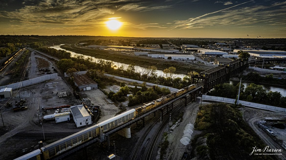 A westbound Union Pacific mixed freight heads northbound at Santa Fe Junction as the sunsets at Kansas City, KS, on October 16th, 2025.

I’m told that Santa Fe Junction sees on average over 75 trains a day and it hosts the double decked railroad (ATSF Double Deck Railroad) bridge that crosses the Kansas River into Missouri, a triple crossing in addition to Tower 3, which is used by maintenance of way these days. The junction is partly in Missouri and Kansas and sees BNSF, UP, KCT, Amtrak, KCS, NS and CP traffic, from what I saw during my visit.

According to the website railfanguides.us Santa Fe Junction Interlocking is easily the busiest location for trains in Kansas City and trains from any of the five railroads which jointly own KCT can be seen here. Tower #3 was closed in 1969 when a central dispatching center replaced it and all the other towers KCT had at the time.

The black bridge is KCT’s double deck, double track crossing of the Kansas River. The odd-looking silver towers on the bridge are lift mechanisms to raise the bridge in the event of flooding and are not connected most of the time. The upper deck line was primarily used by passenger trains from UP and Rock Island, moving to and from Kansas through the KC Union Station. Today primarily freight trains use this bridge.

The tracks through the junction have been reduced or changed around over the years, but the area remains one of KC’s Busiest locations.

Tech Info: DJI Air 2S Drone, RAW, 22mm, f/2.8, 1/3200, ISO 100

#trains #railway #JimPearsonPhotography #trainsfromadrone